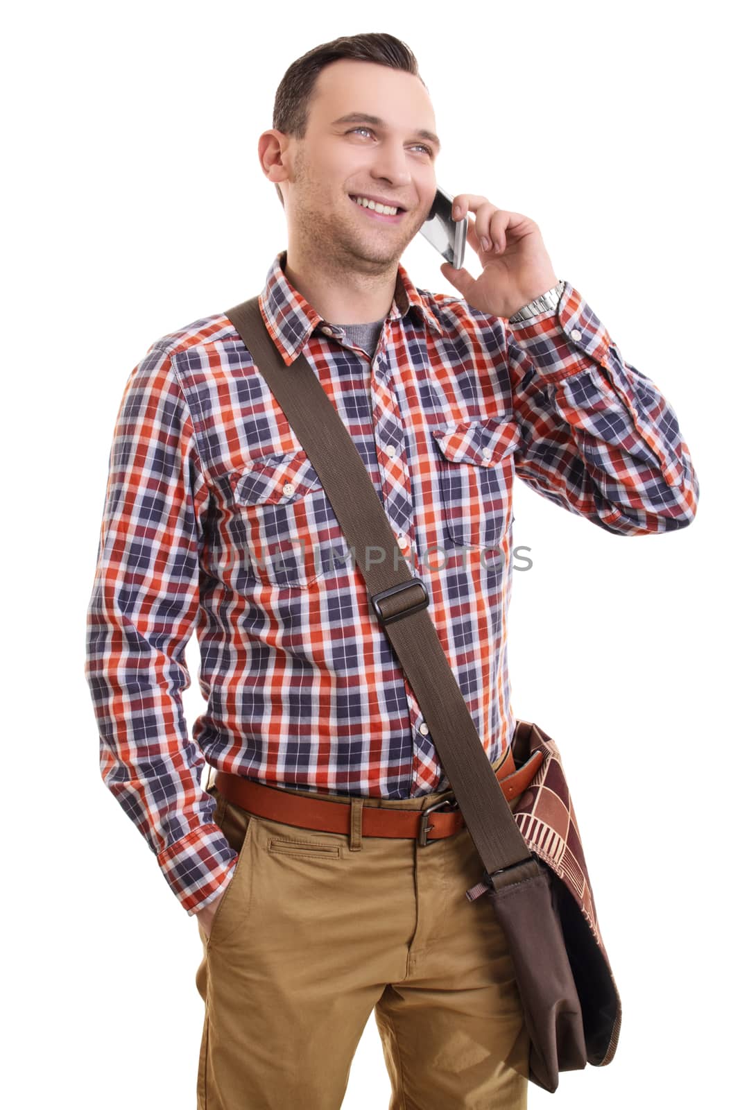 Communication concept. Portrait of a handsome smiling casual man in plaid shirt and a shoulder bag talking on mobile phone, isolated on a white background.