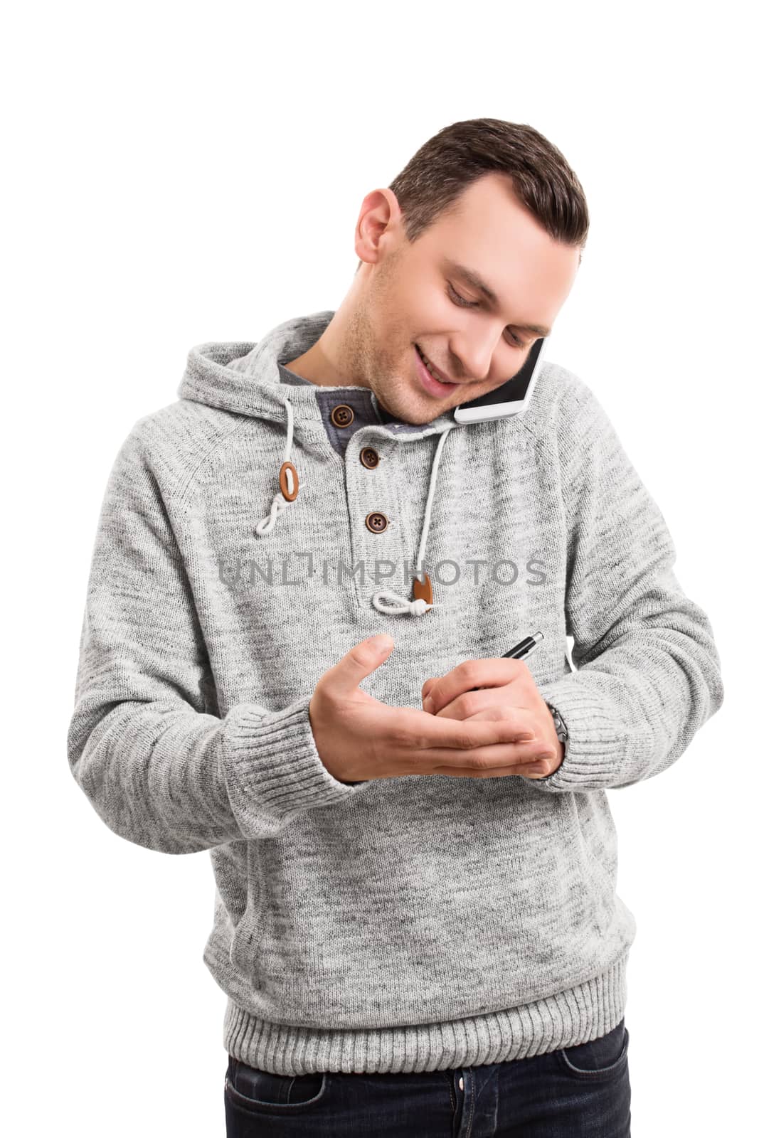 Portrait of a confident smiling man or student in casual clothes talking on mobile phone taking a message or note on his palm, isolated on a white background. Young man talking on the phone writing something on his hand.
