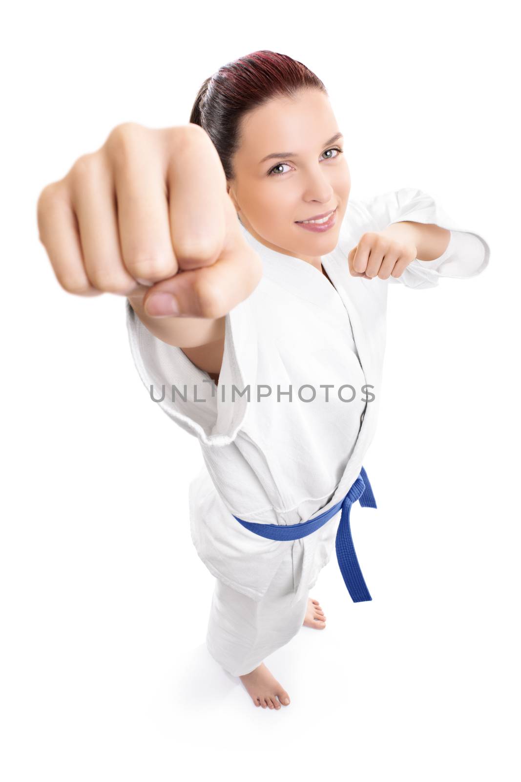 Top down portrait of a beautiful young female fighter in white kimono attacking isolated on white background. Girl in white kimono with blue belt.