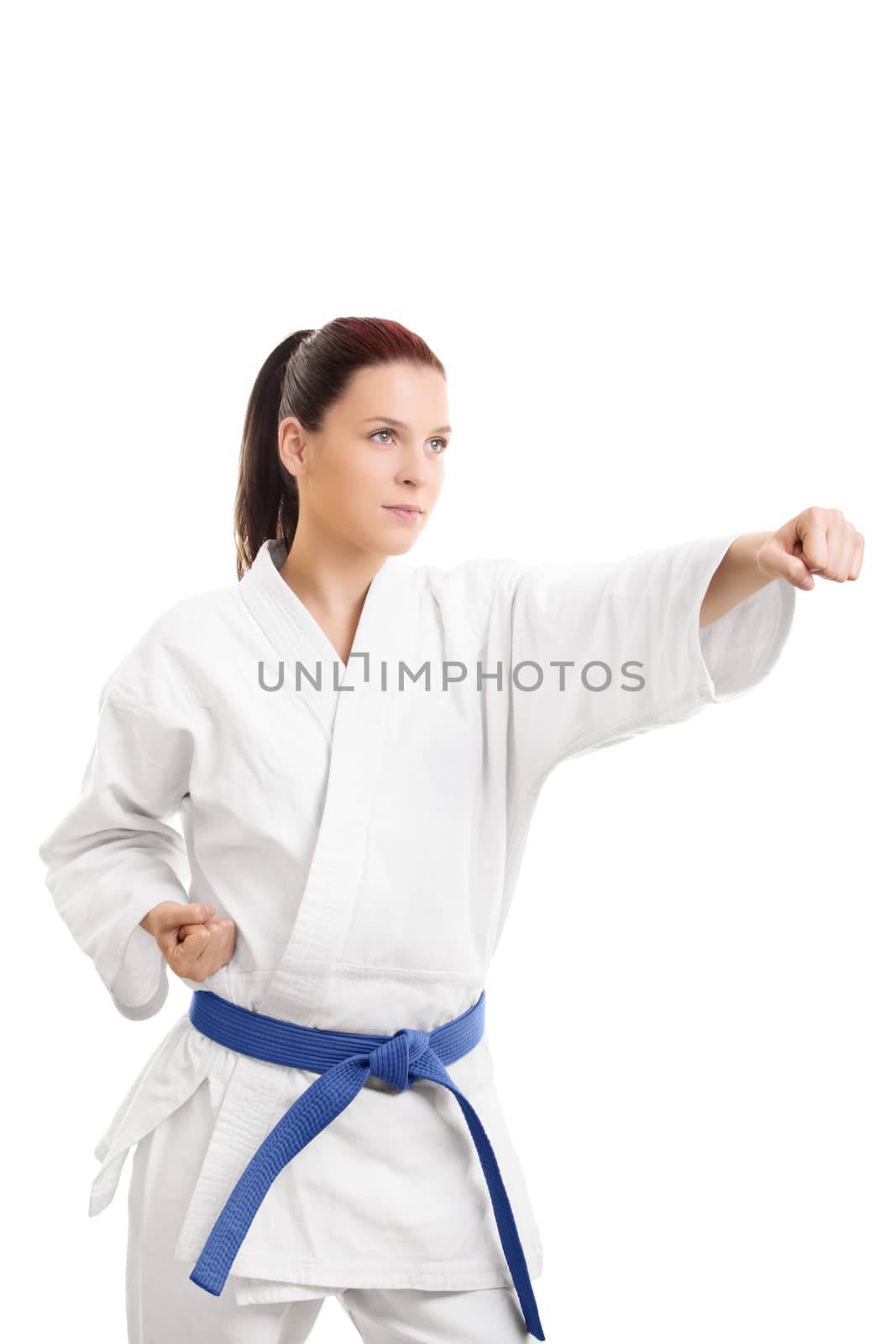 Martial arts concept. Portrait of a beautiful young girl in a kimono with blue belt punching, isolated on white background.