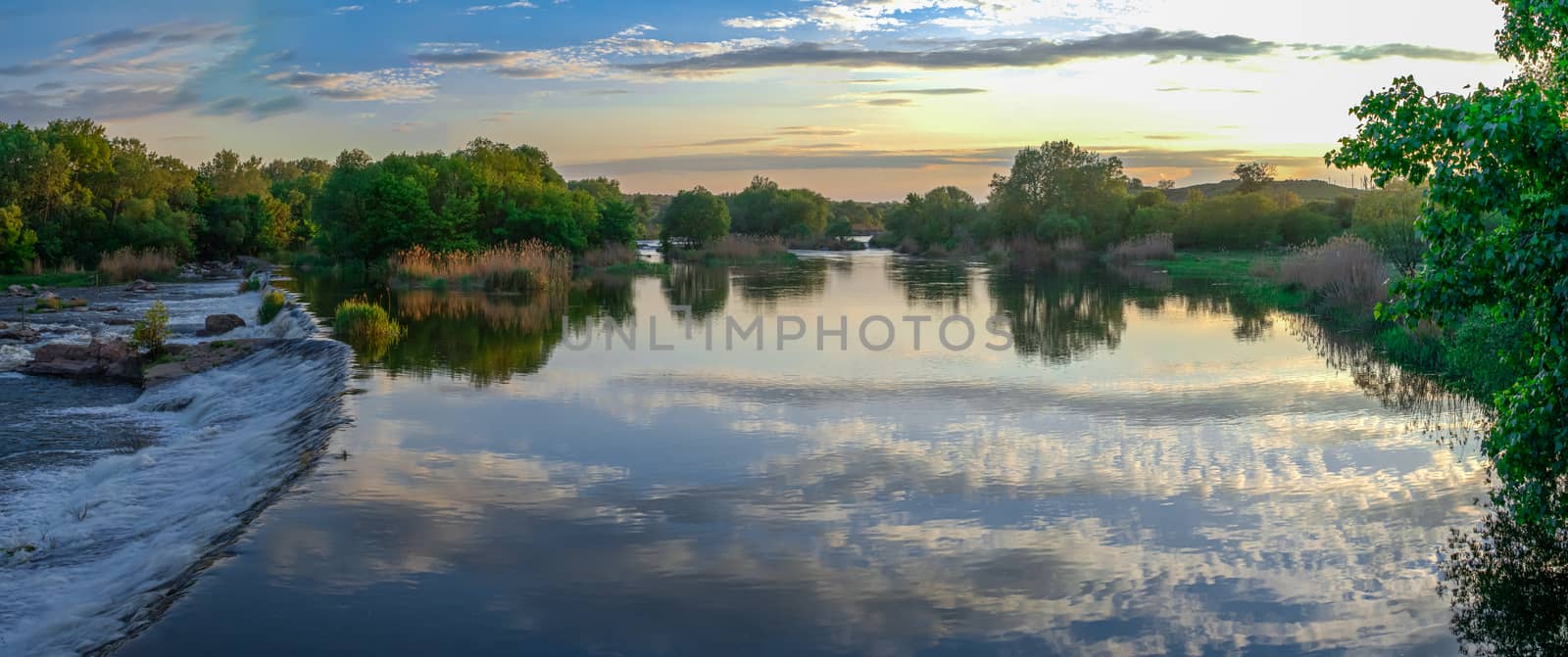 Beautiful view of the dam on the Southern Bug River at sunset. Village of Migiya, Ukraine, on a sunny summer evening