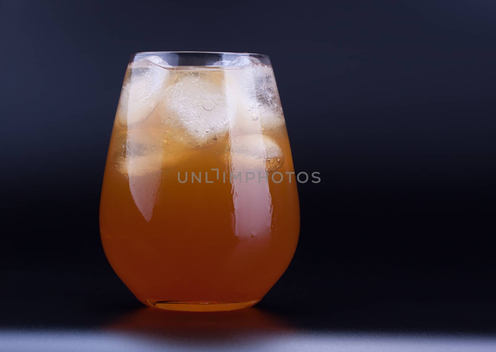 Big glass of ice tea with ice cubes, black background