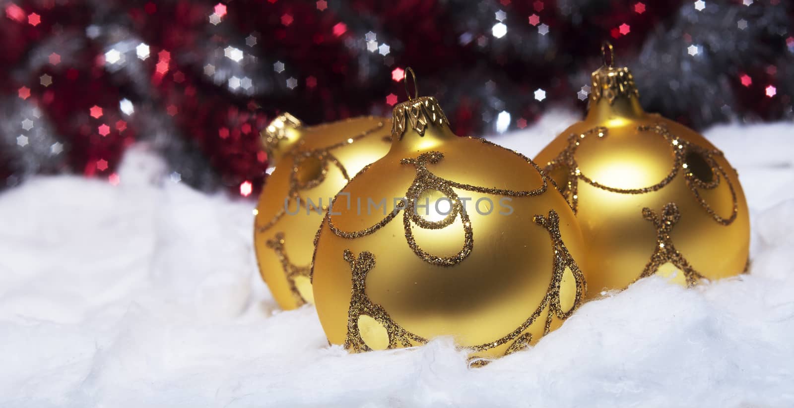 Gold Christmas balls in the snow on a creative silver-red background