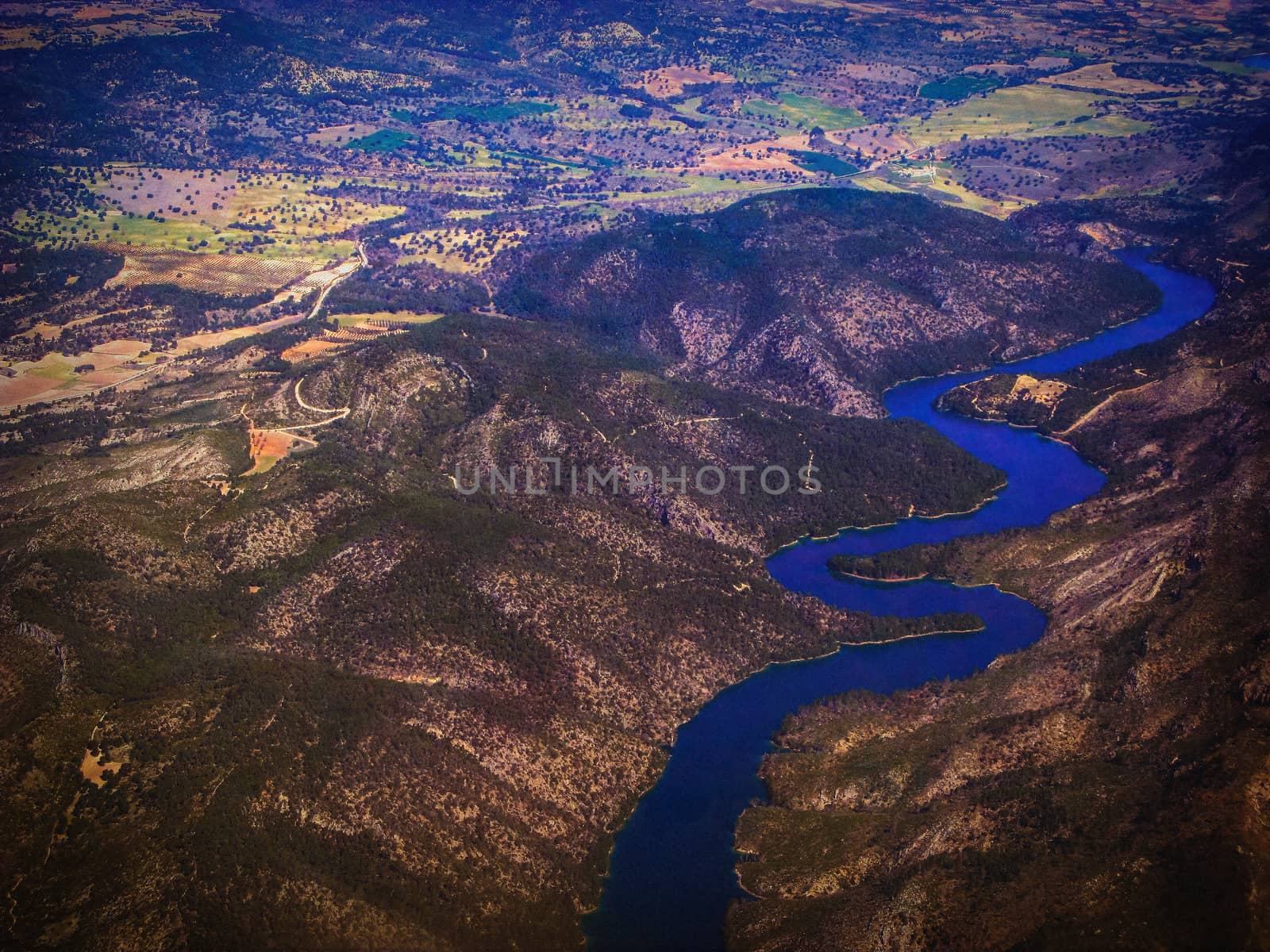 Top view of the ground from the plane. European landscape. Colorful pattern of trees, fields, rivers and lakes. Soft focus.