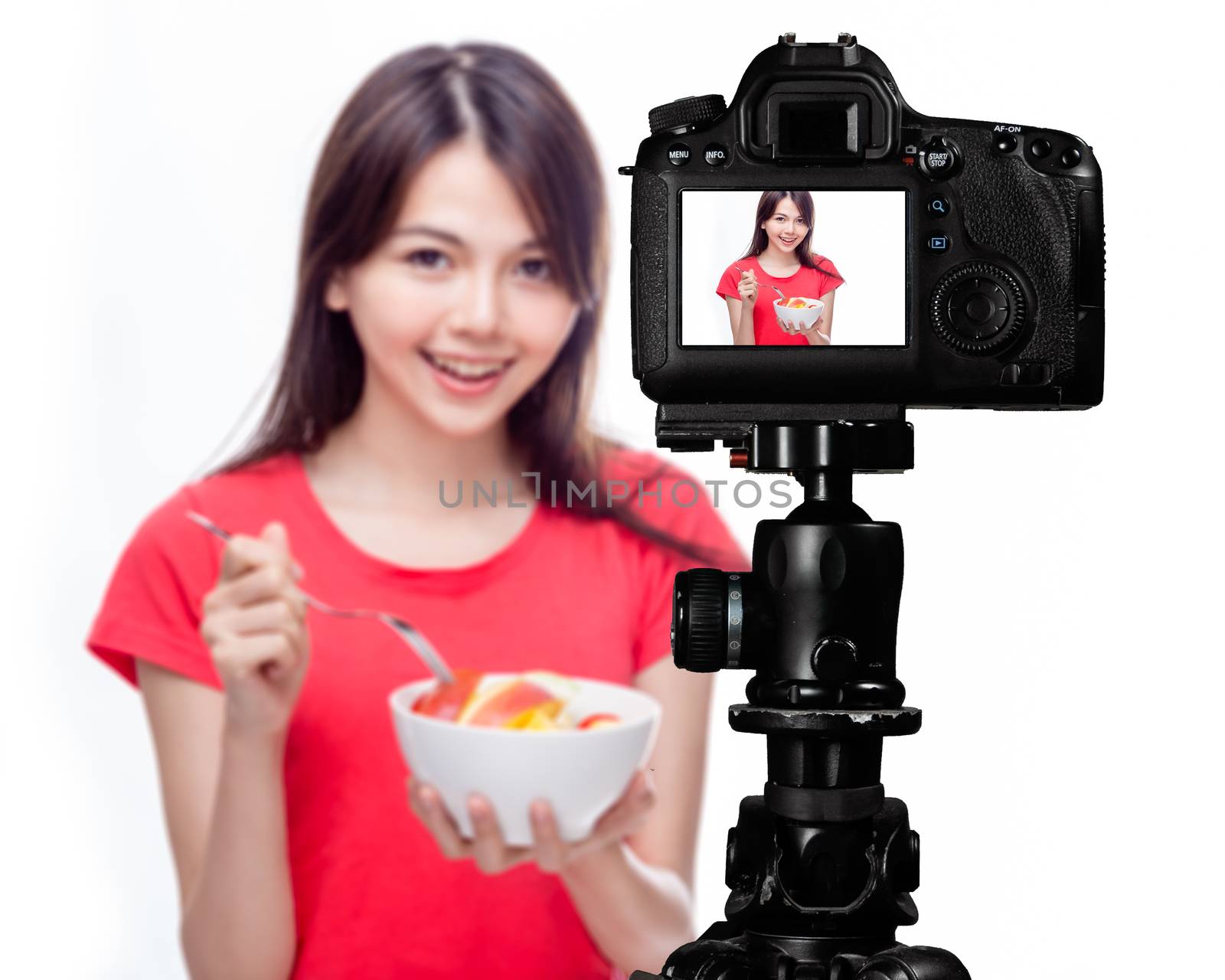 Asian food vlogger with fruit salad behind camera, social media production concept