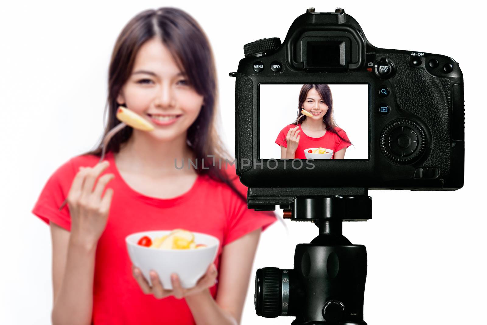 Asian food vlogger with fruit salad behind camera, social media production concept