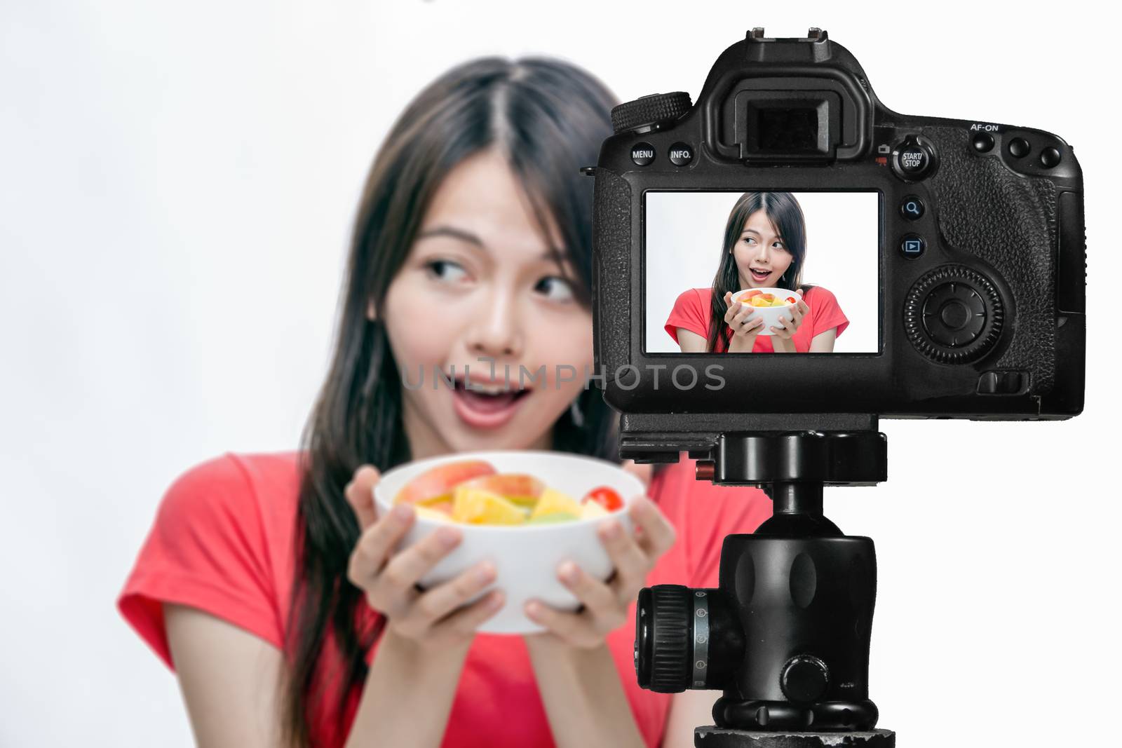 Asian food vlogger with fruit salad behind camera, social media production concept