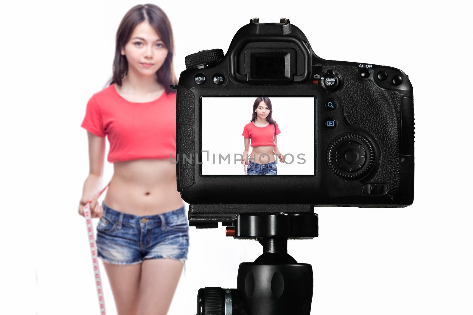 Asian vlogger measuring waist behind camera, social media production concept