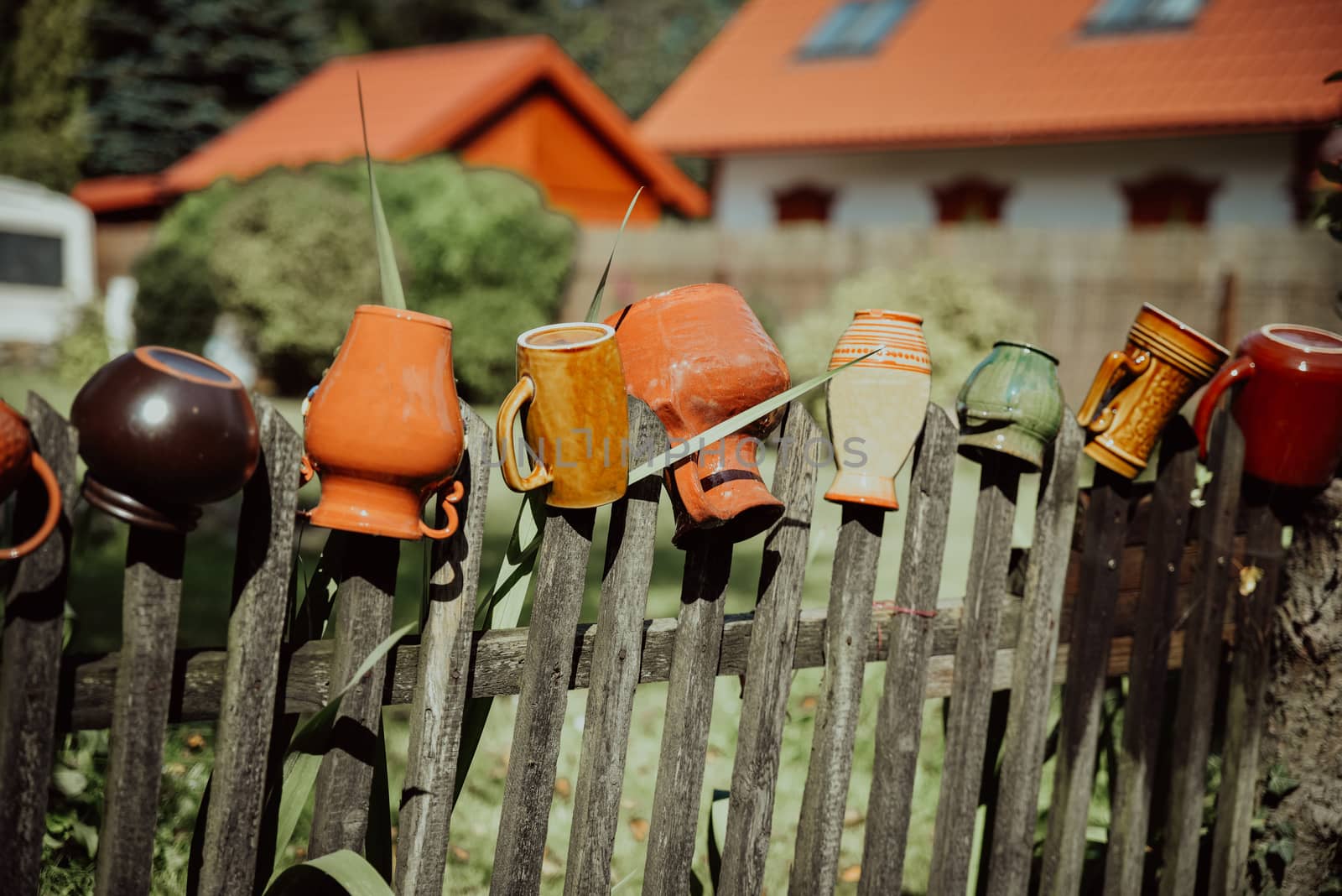 Old clay jugs on wooden fence in rural environment
