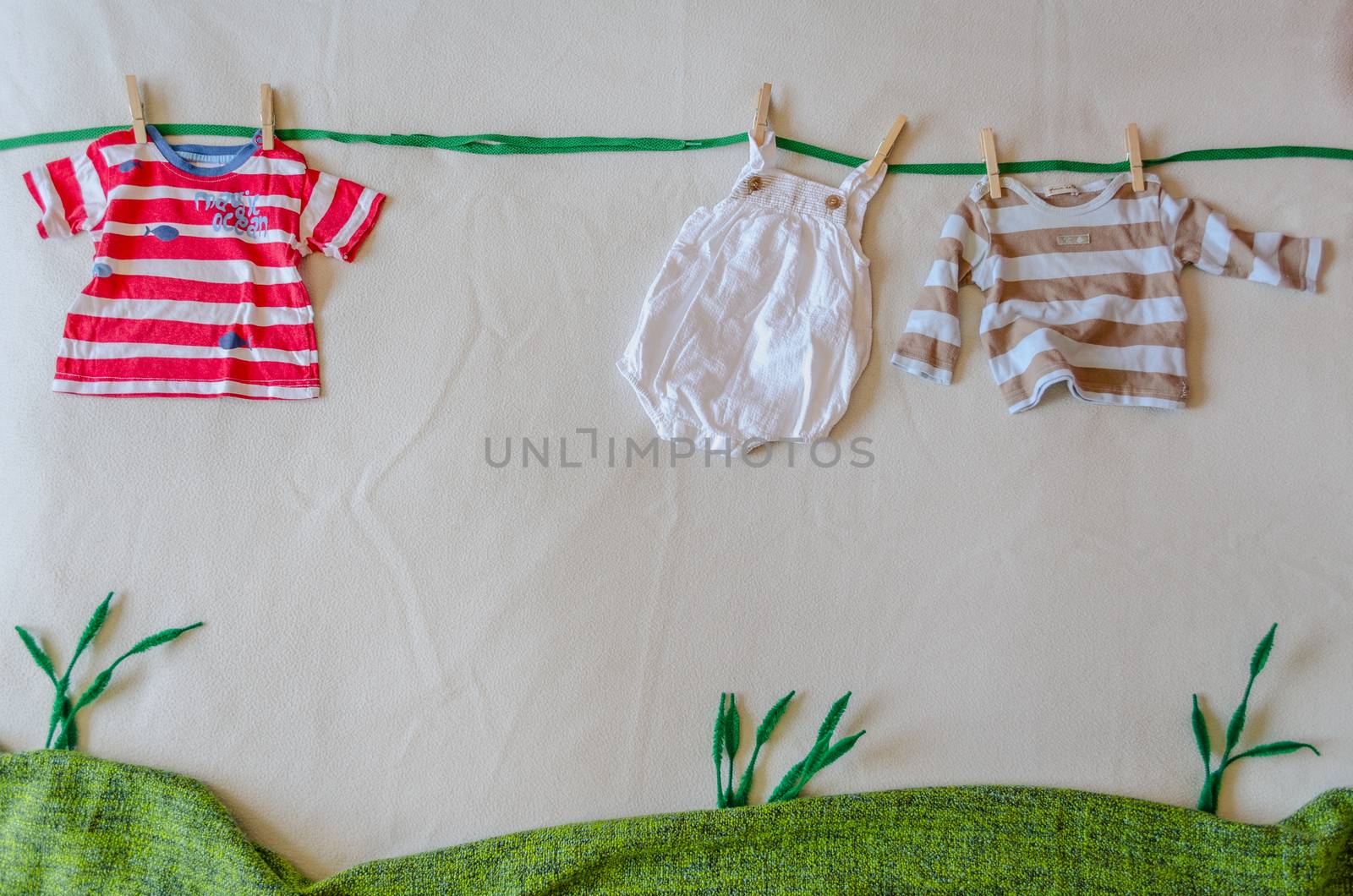 Mock scene made with babys clothes simulating a clothesline on a green meadow by mikelju