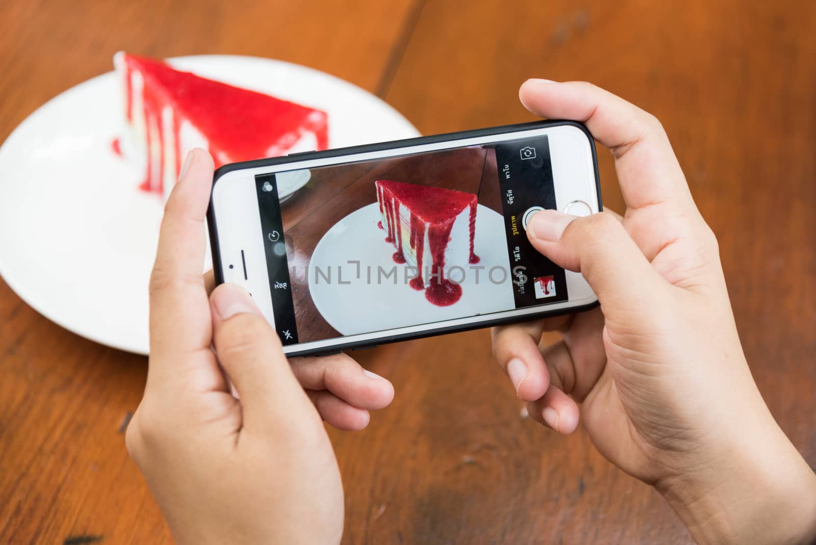 Taking photo of Sliced tasty strawberry cake on wooden table background