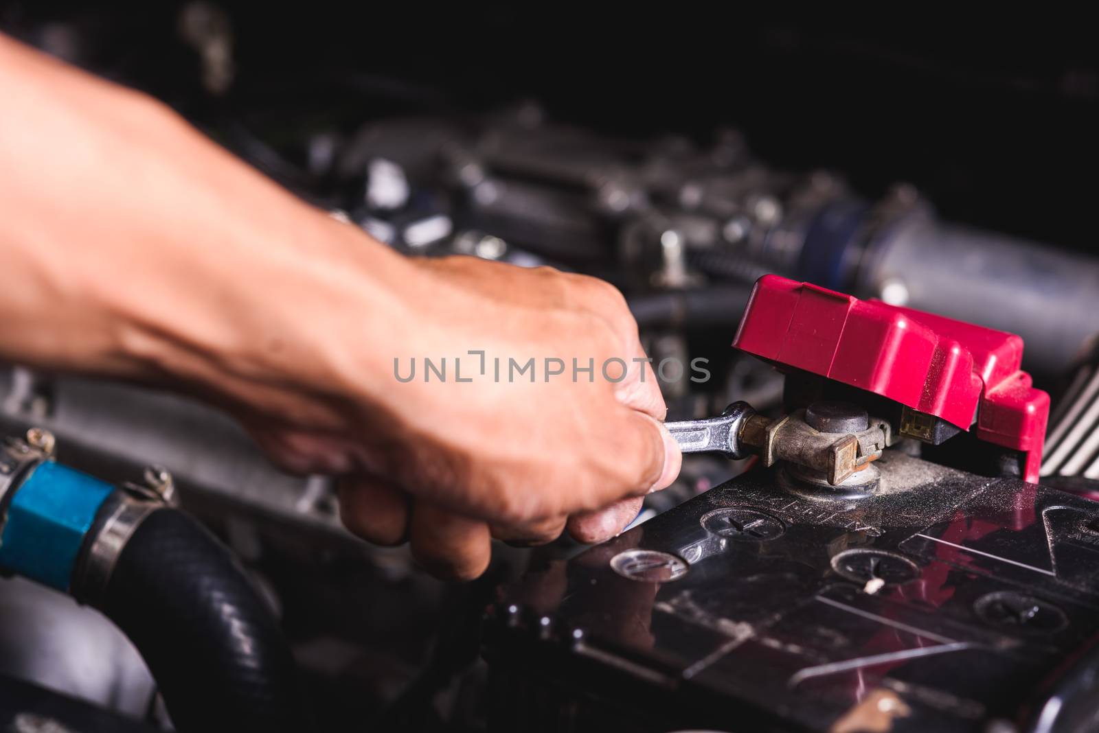 Hand of technician service check battery and turn battery screw loose in garage
