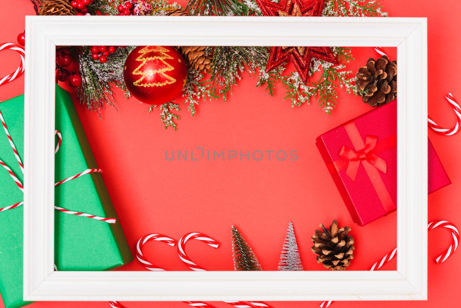 Christmas composition decorations, with white Photo frame square and fir tree branches on red background. Merry Christmas concept. Copy space for text