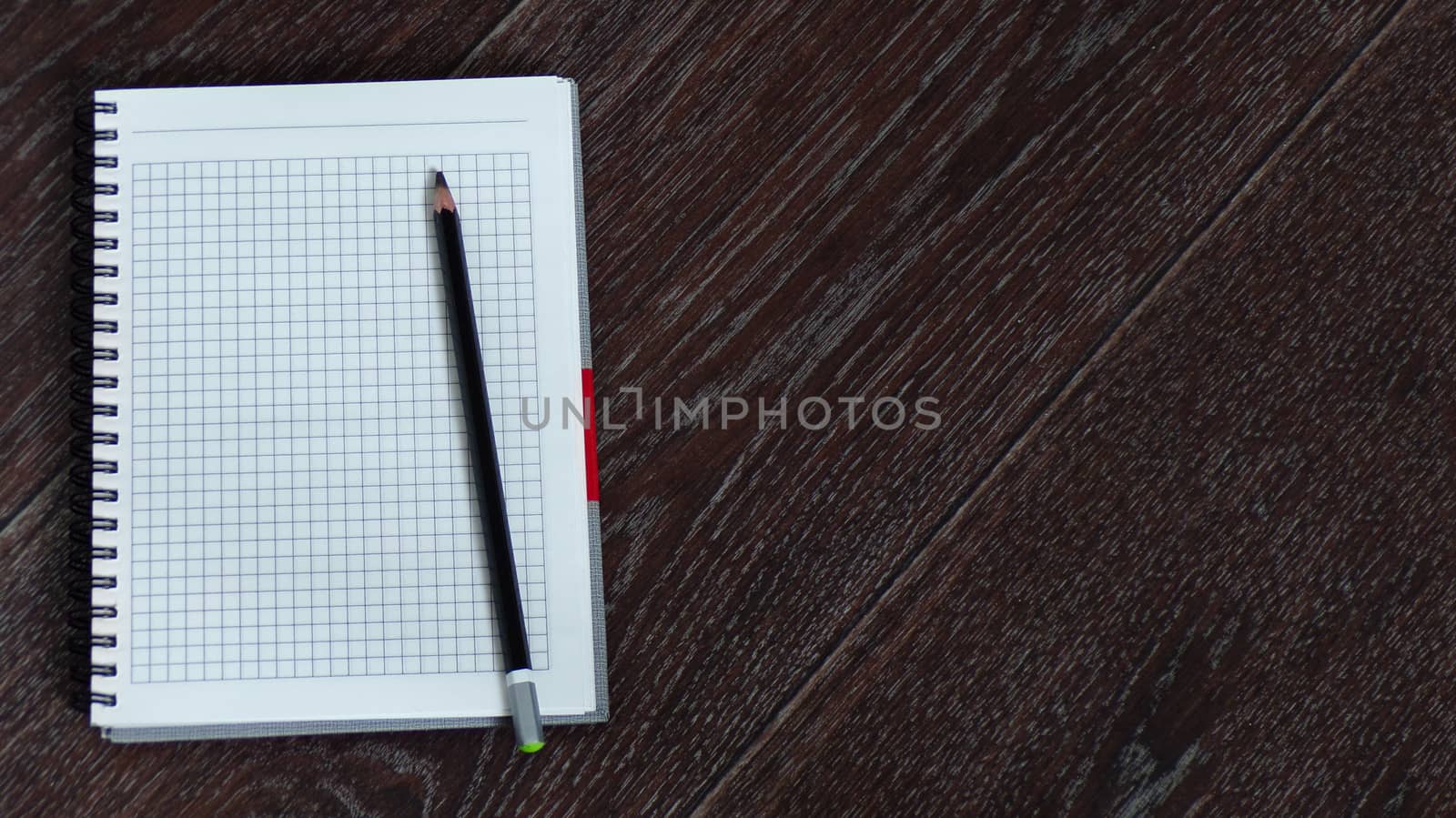 A notebook with a pen lies on a wooden table, a copy of the space, an empty space for text. The spiral notebook on the working place of accountant. Wide-angle and panoramic photos.