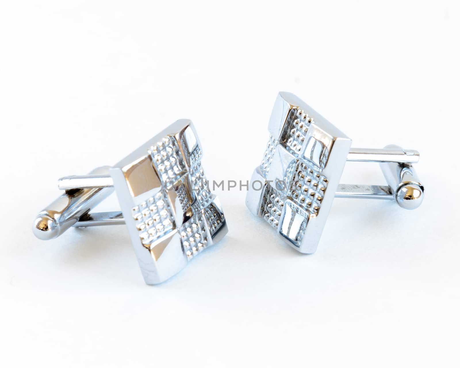 Close-up single pair of modern stainless steel cufflinks isolated on white background. Lifestyle trendy clothing accessories dress with clipping path and copy space.