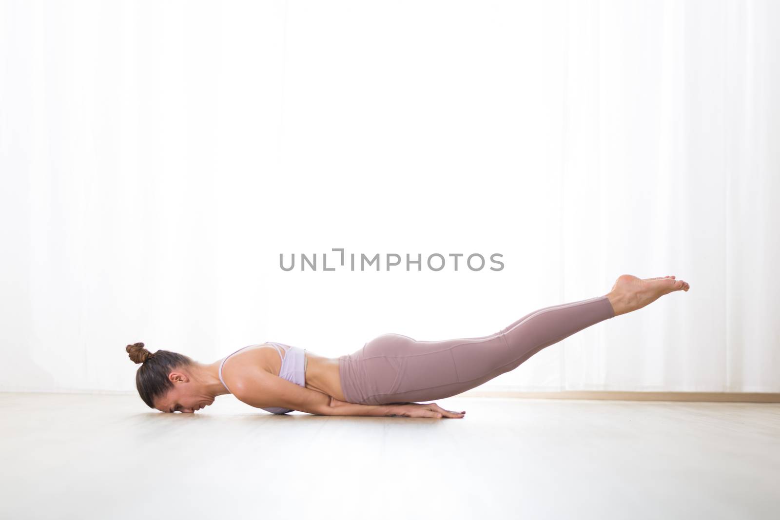 Portrait of gorgeous active sporty young woman practicing yoga in studio. Beautiful girl practice Poorna Salabhasana, ful locust yoga pose. Healthy active lifestyle, working out indoors in gym.