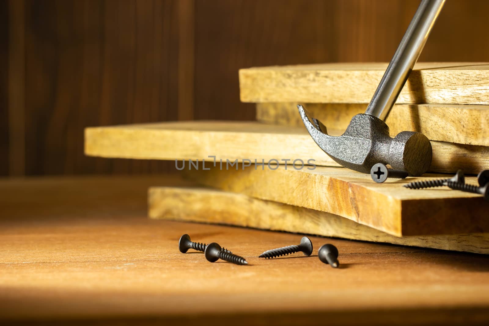 Hammer and screw on lumber in lighting and shadow of the sunshine in morning. The concept of woodcraft or carpentry.