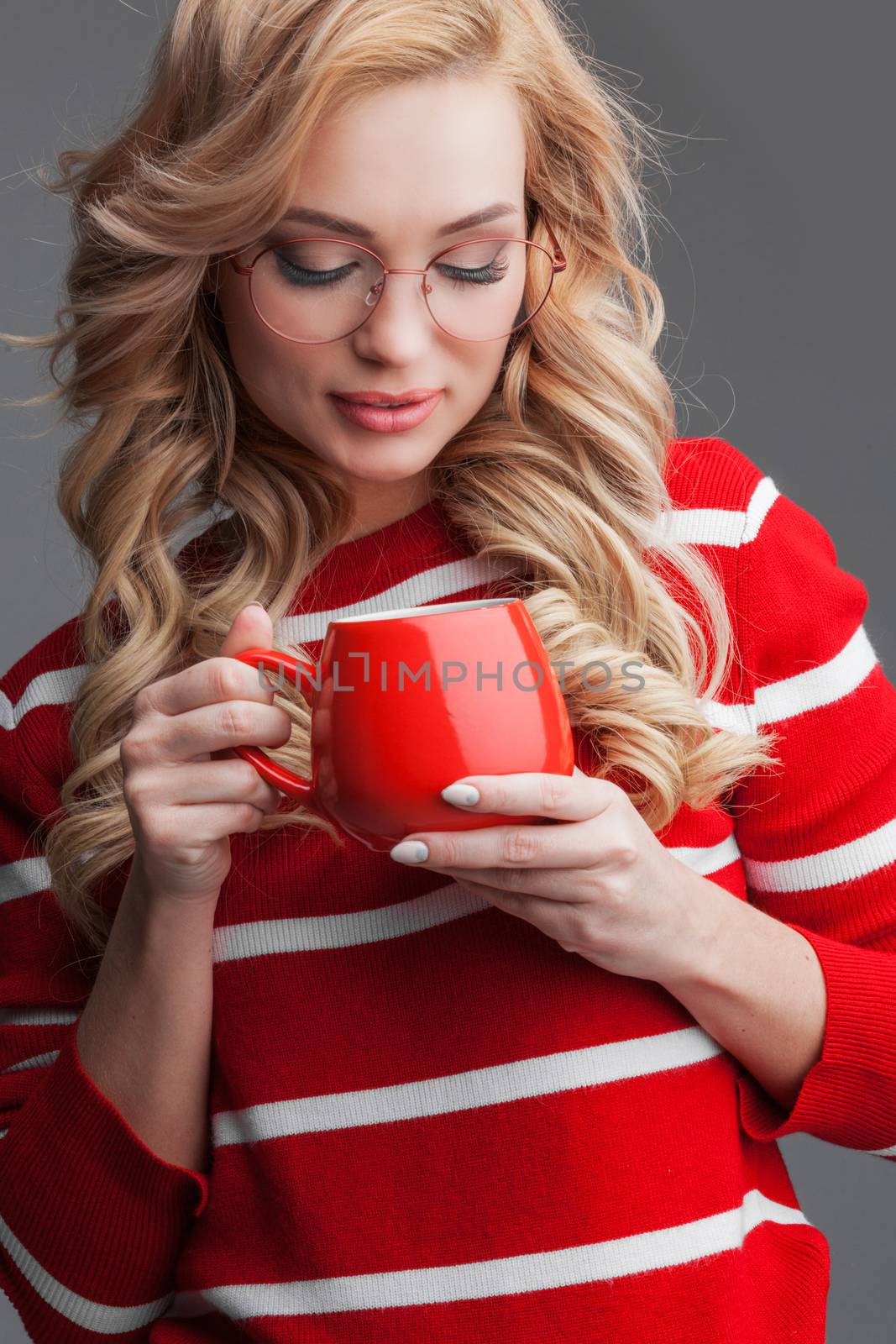 Beautiful blonde woman in glasses holding red cup of drink Christmas Valentines day concept