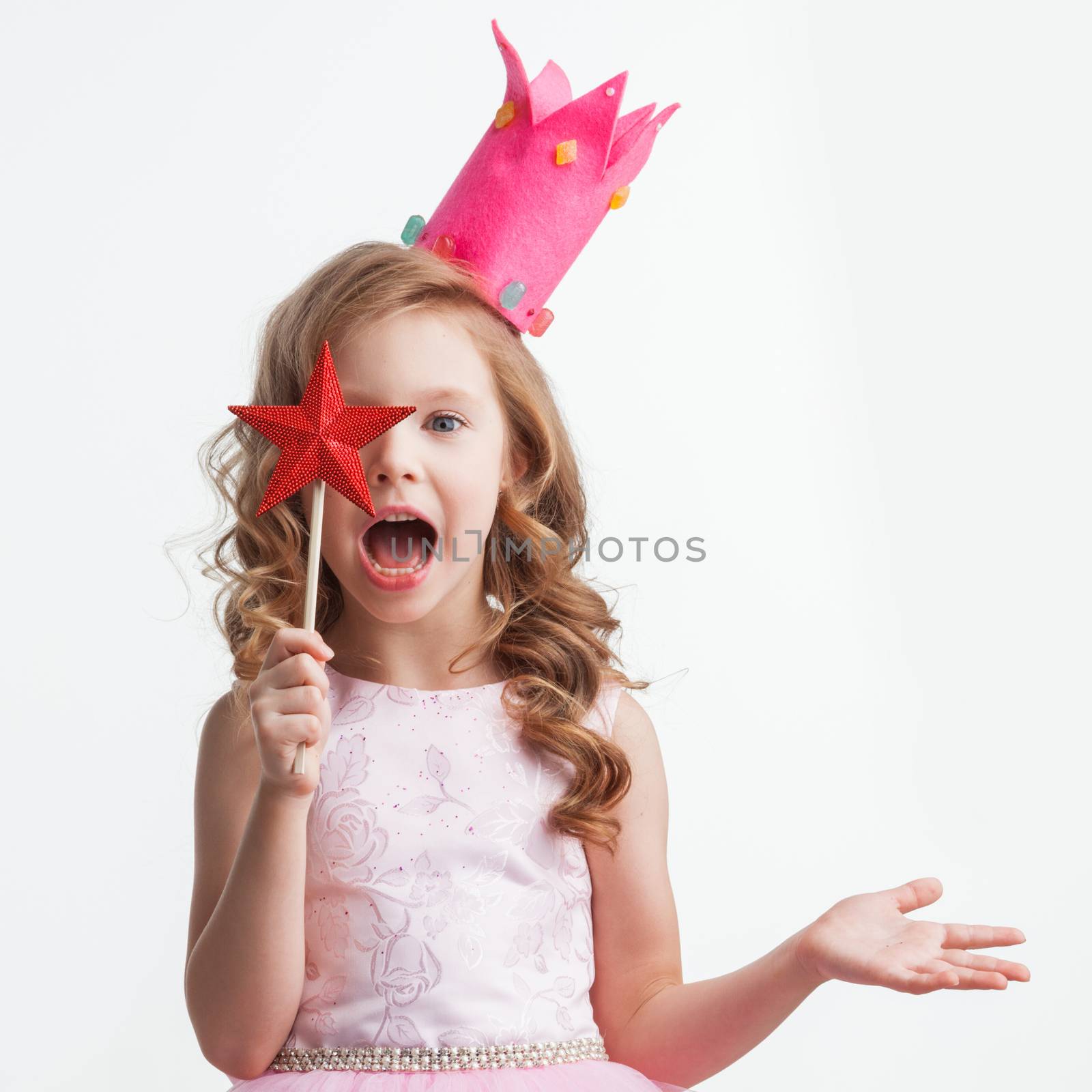 Beautiful little candy princess girl in crown holding star shaped magic wand and making a wish spell isolated on white background