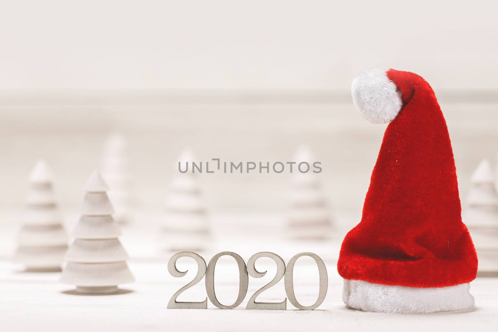 Conceptual 2020 new year background with small wooden fir trees 2020 number and red santa claus hat
