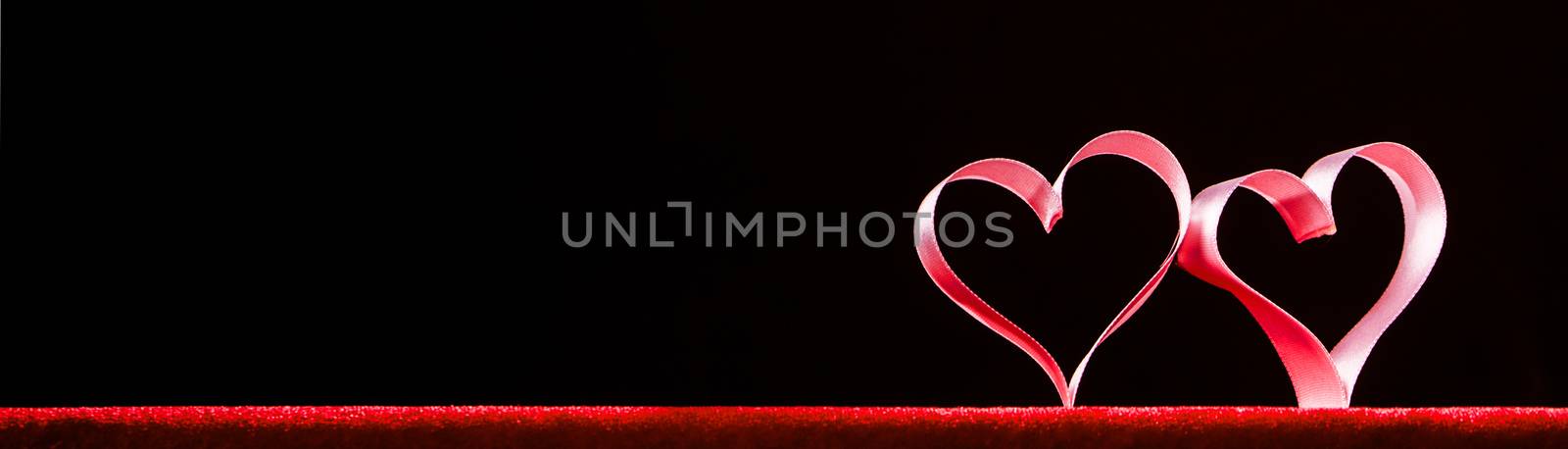 Two red ribbon hearts on black background with copy space for text, Valentines day concept