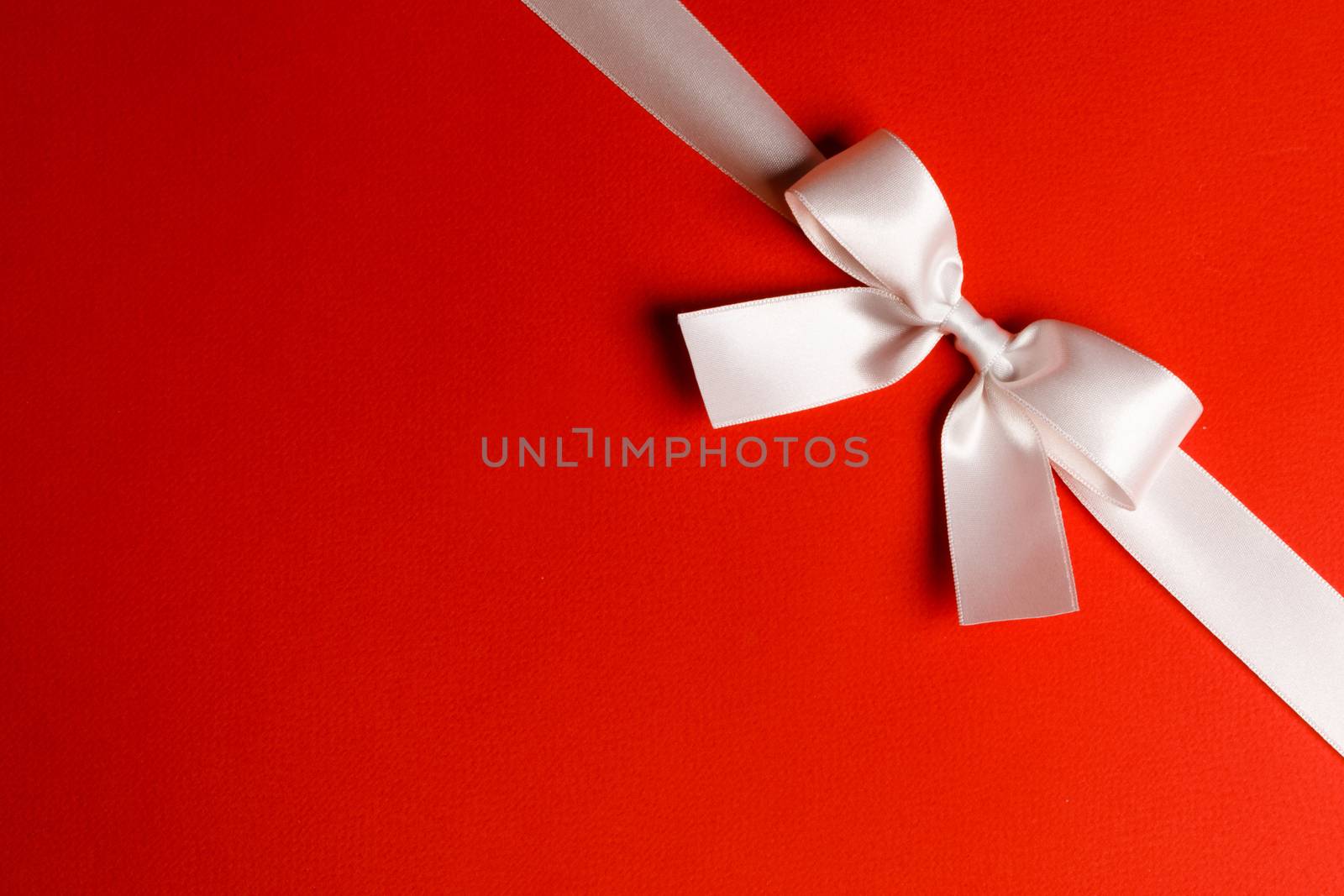 Elegant satin white ribbon bow on red background