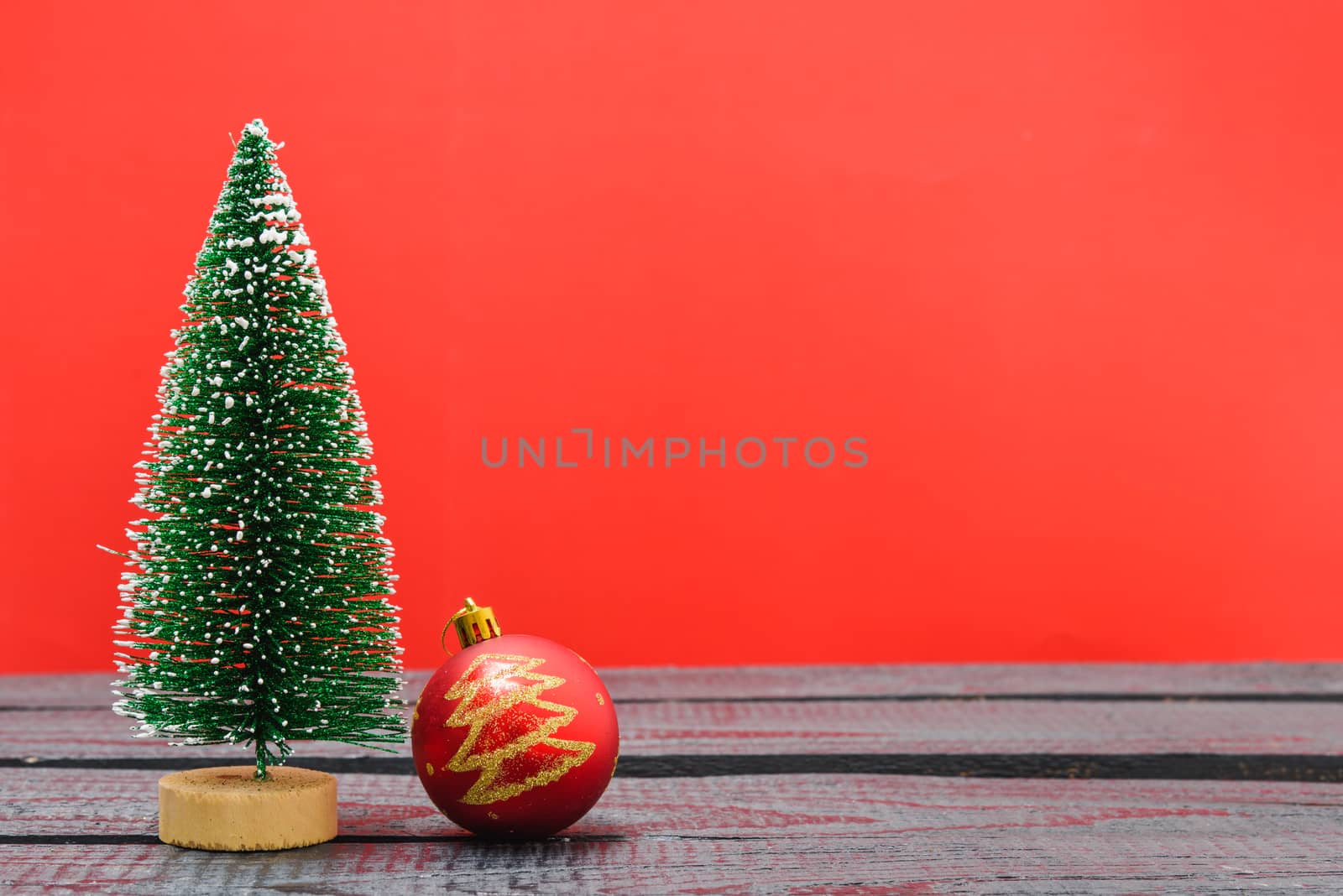 Christmas composition decorations, minimal green fir tree branches with snow and ball on red background. Merry Christmas concept. Copy space for text
