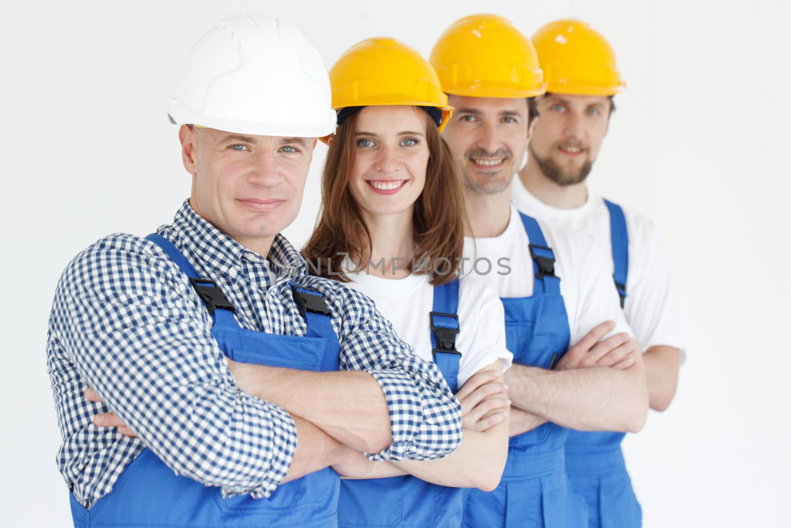 A friendly young team of construction workers with arms crossed standing in a row and smiling