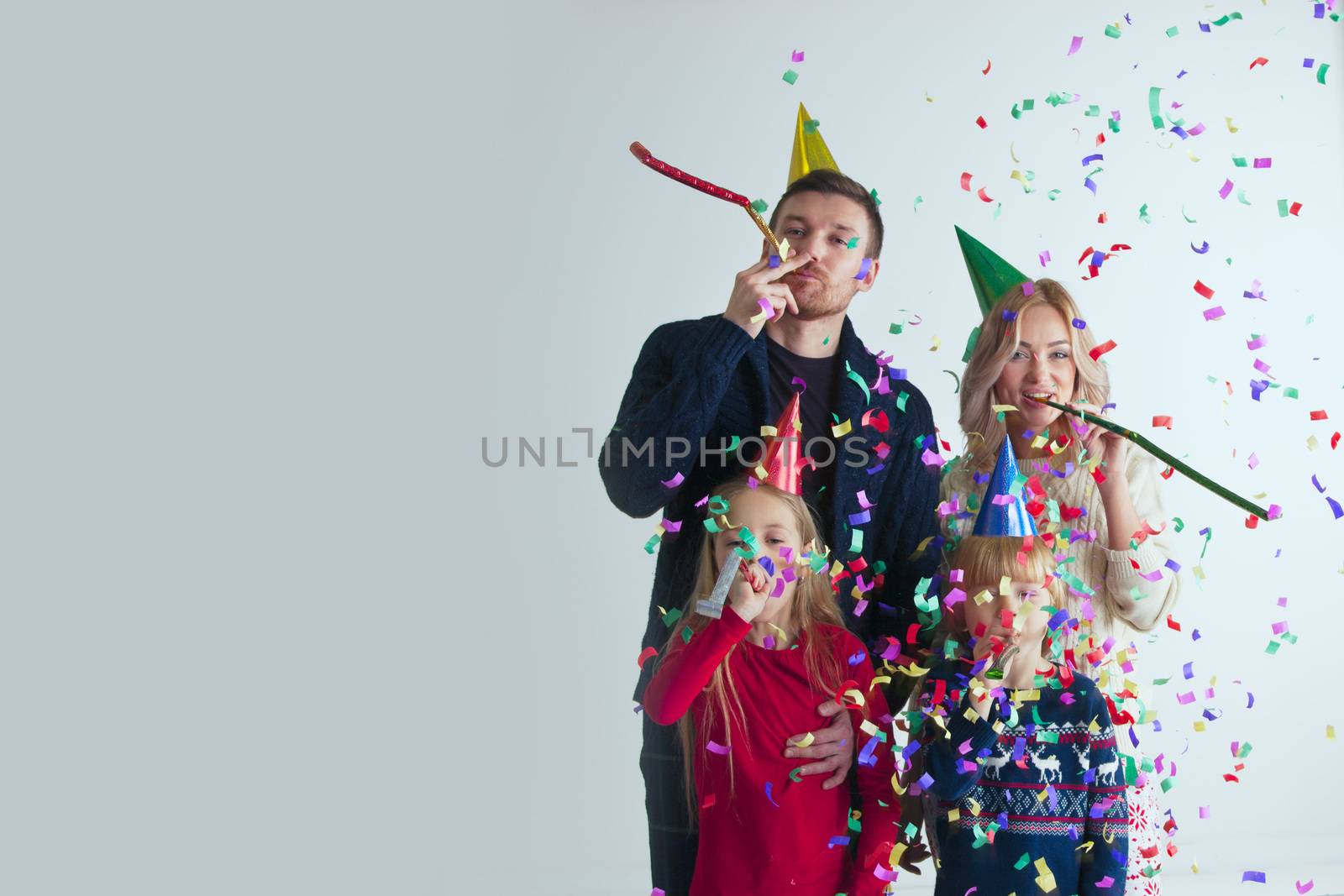 Family blowing party trumpets with confetti celebrating new year