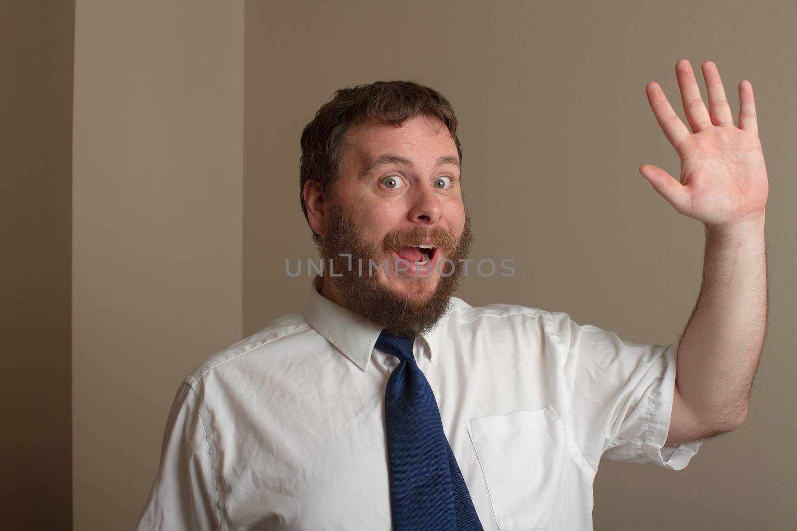 man holding up his hand to wave with a fake smile