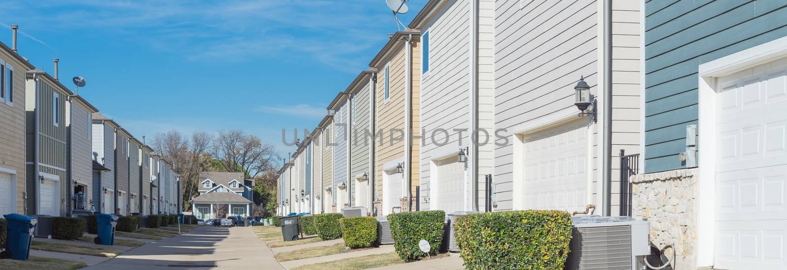 Panorama back alley of new development residential community, line of two-car garage door in Coppell, Texas. Colorful two story houses row well trim landscape near downtown Dallas, outdoor AC units