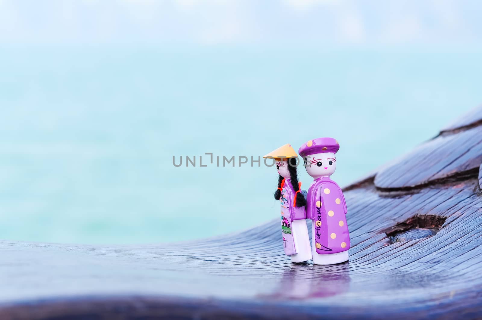 Handicraft Vietnamese magnetic wooden puppets in traditional costumes with natural ocean background. Famous Vietnamese dolls souvenirs. Selective focus on the face of the puppets