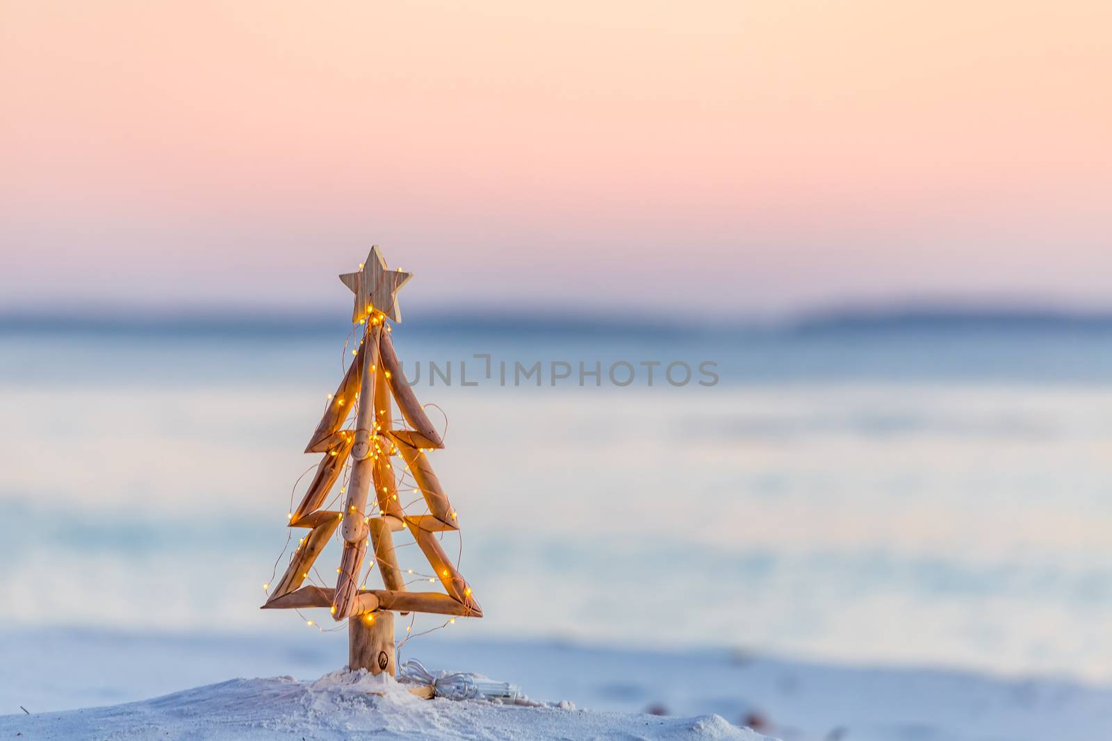 Driftwood rustic Christmas tree with fairy lights on the beach in summer by lovleah