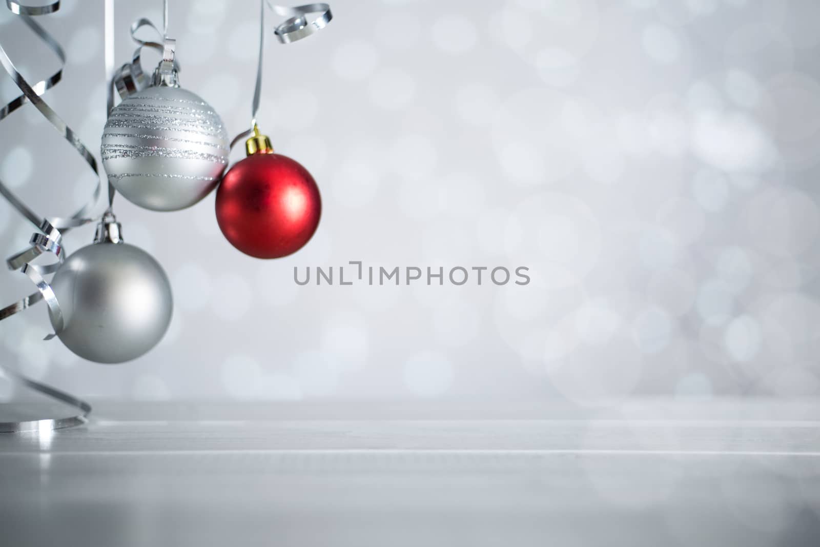 Silver and red Christmas new year balls with curly streamer ribbon bow over glittering bokeh lights background with copy space for text