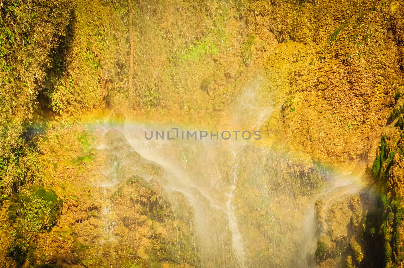 Rainbow over small white current at Dai Yem (Pink Blouse) waterfall in Muong Sang Commune, Moc Chau, Son La, Vietnam. Fall gushes down its slope with small and medium rocks in various shapes