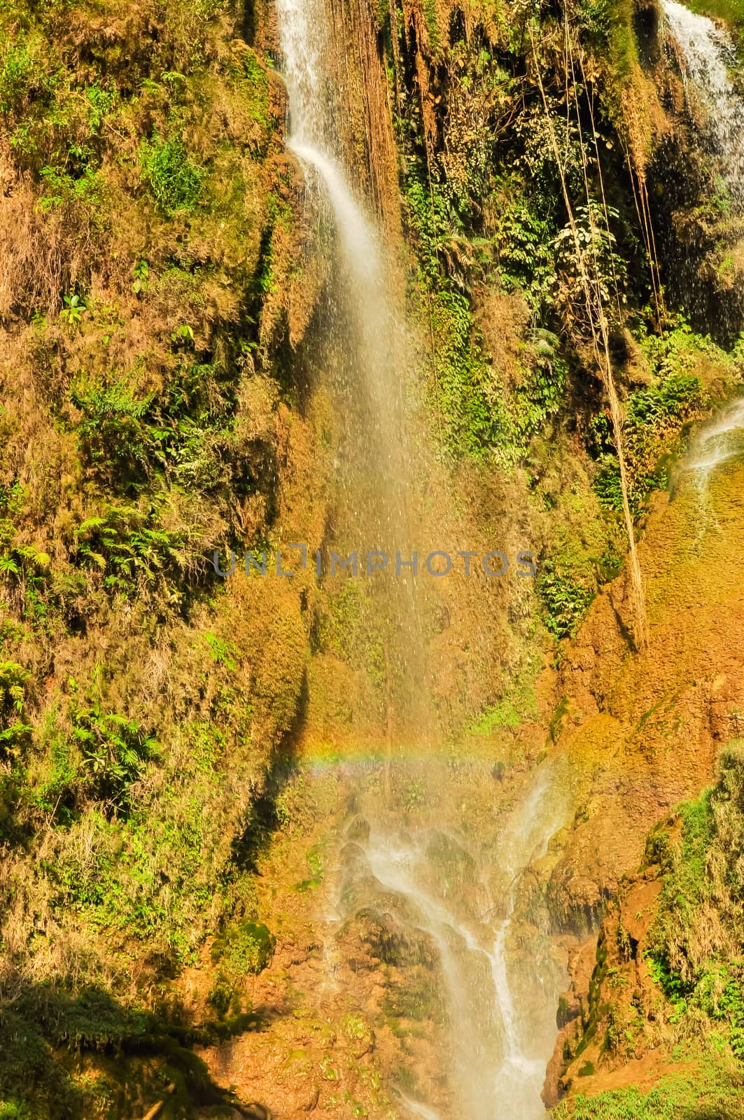 Rainbow over small white current at Dai Yem (Pink Blouse) waterfall in Muong Sang Commune, Moc Chau, Son La, Vietnam. Fall gushes down its slope with small and medium rocks in various shapes