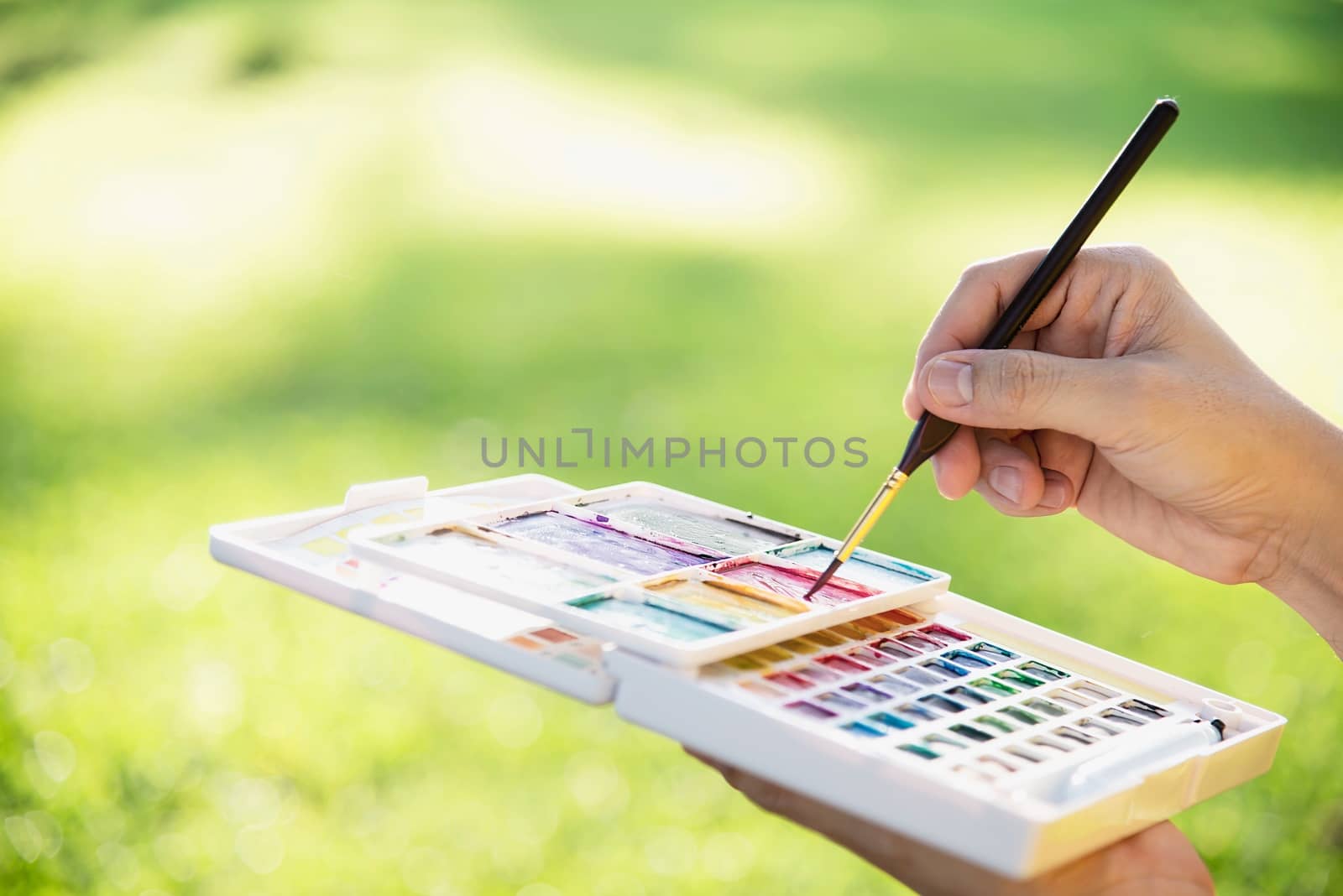 Relax woman painting water colour art work in green garden forest nature - people with creative art in nature stress reduction and meditation concept