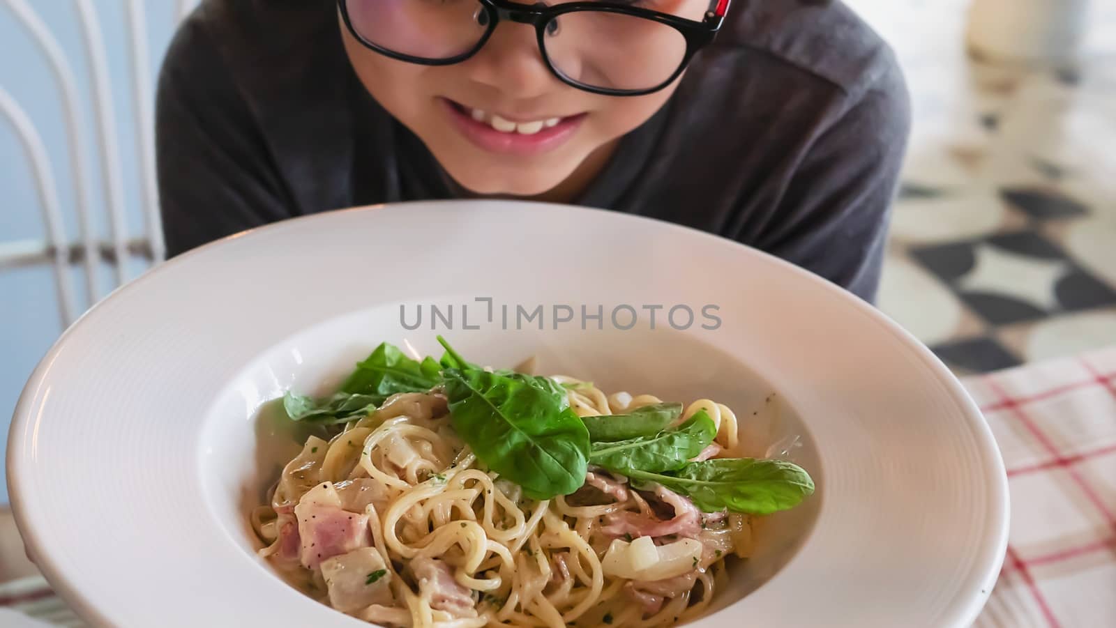 Boy happy eating spaghetti carbonara recipe - people enjoy with famous Italian dish food concept by pairhandmade