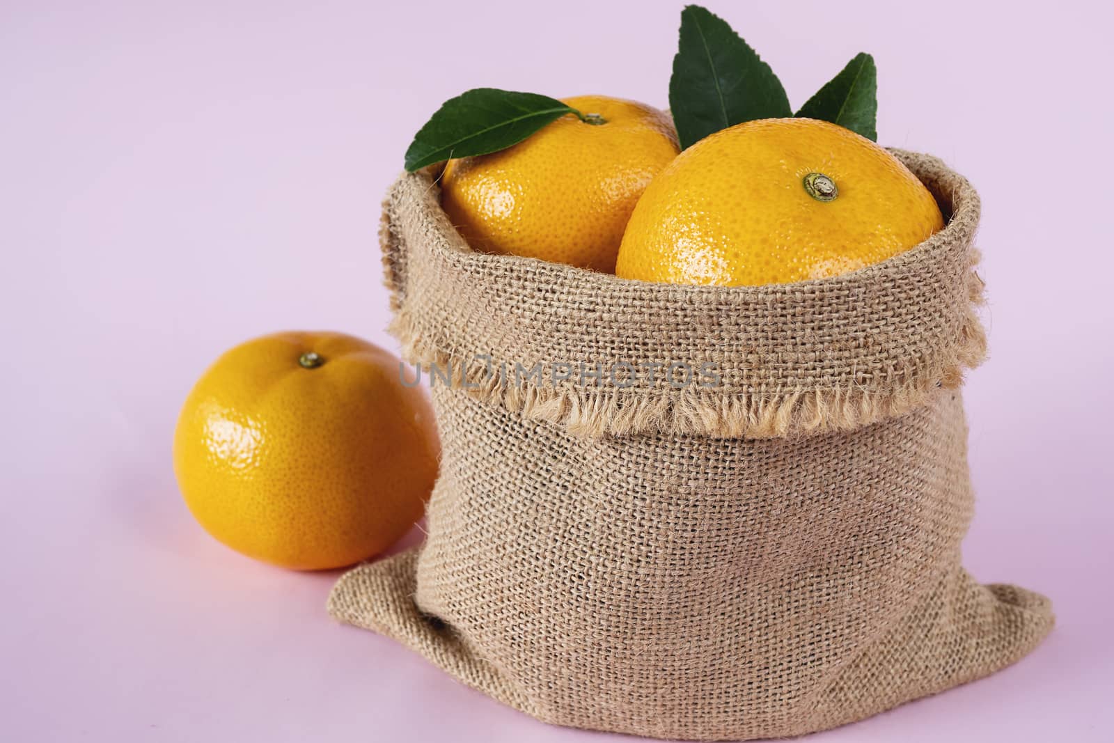 Fresh juicy orange fruit set over light pink background - tropical orange fruit for background use by pairhandmade