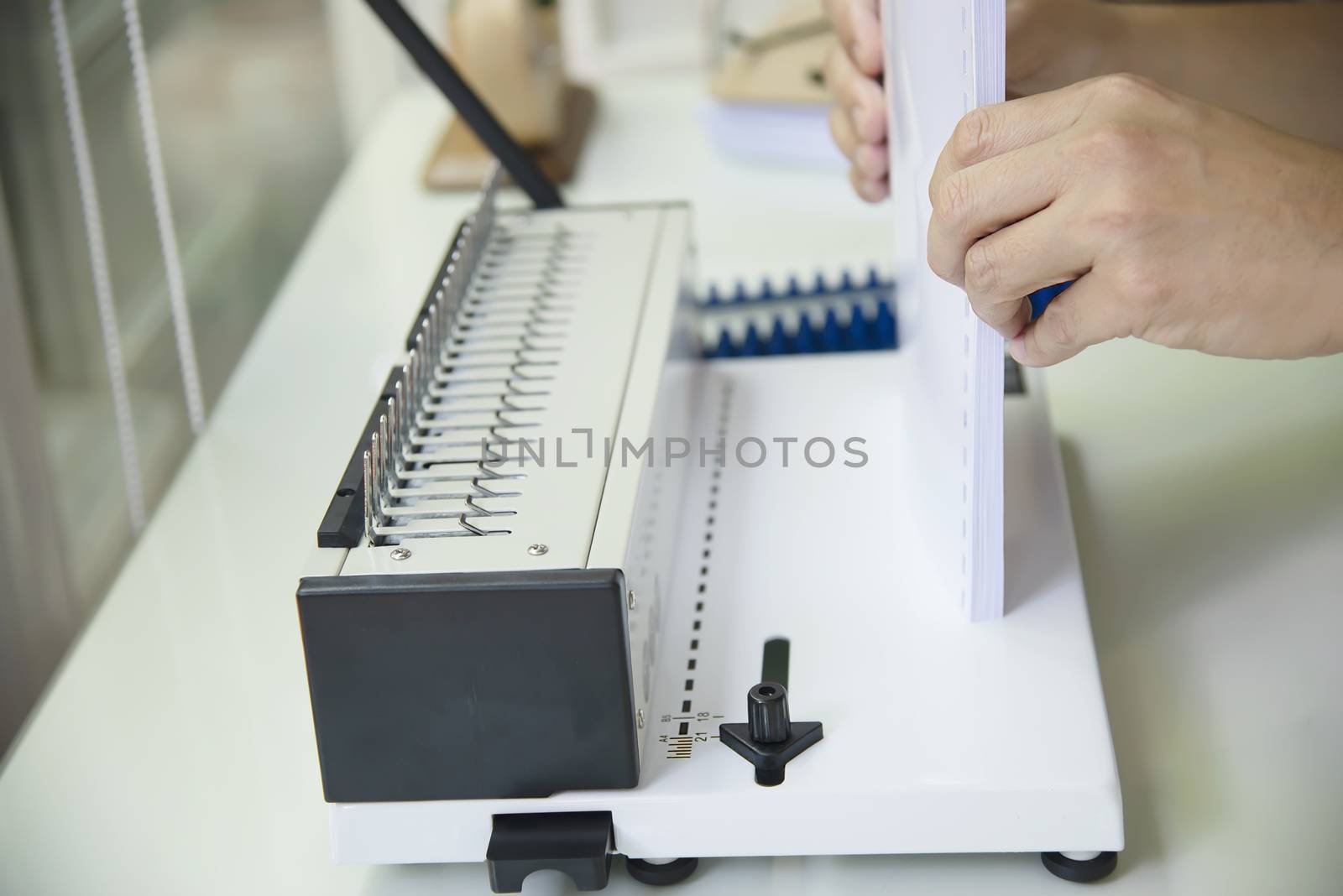 Man making report using comb binding machine - people working with stationary tools concept