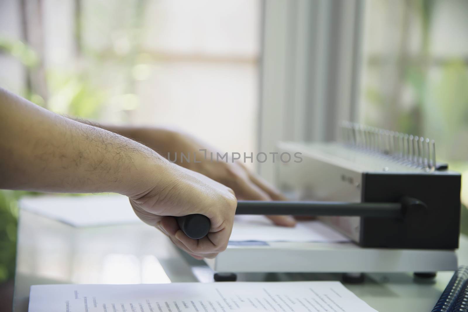 Man making report using comb binding machine - people working with stationary tools concept