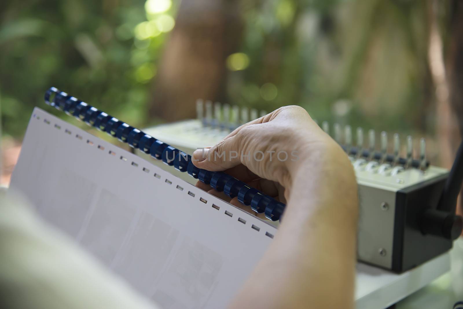 Man making report using comb binding machine - people working with stationary tools concept