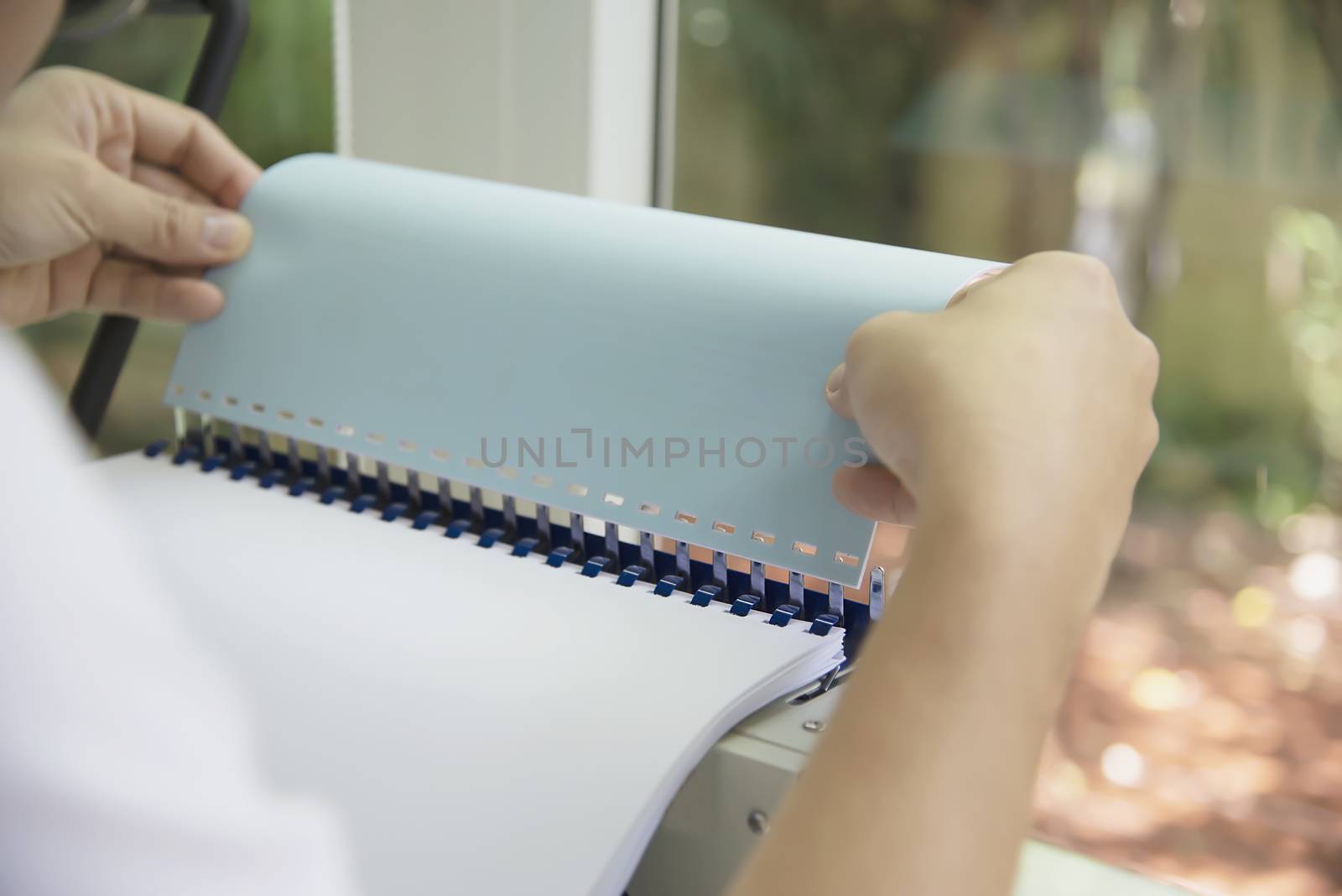 Man making report using comb binding machine - people working with stationary tools concept by pairhandmade