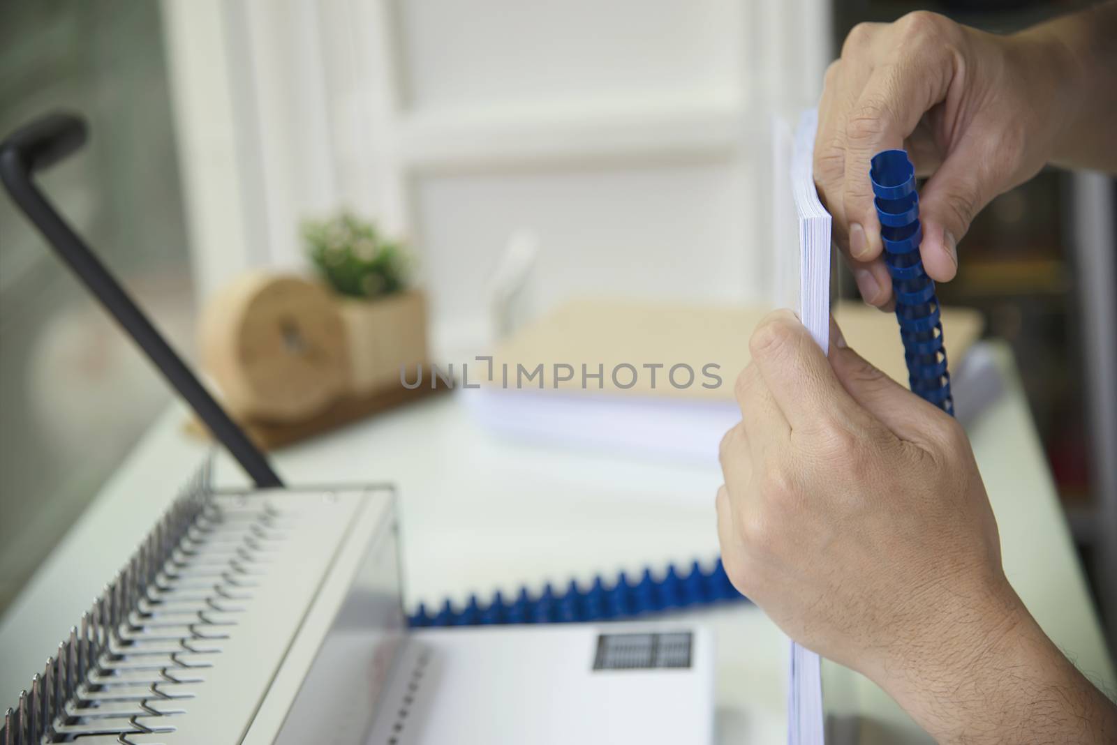 Man making report using comb binding machine - people working with stationary tools concept by pairhandmade