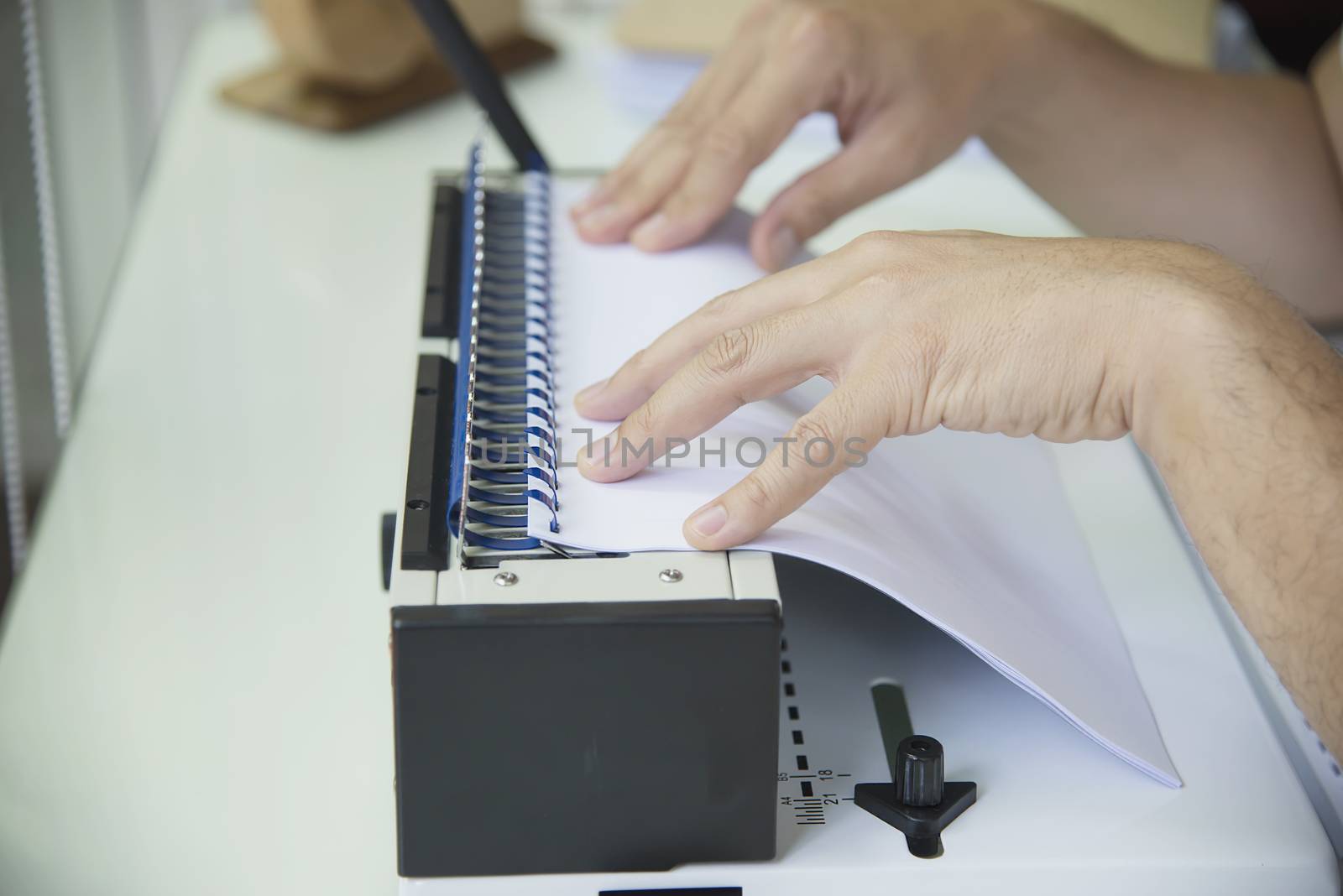 Man making report using comb binding machine - people working with stationary tools concept by pairhandmade