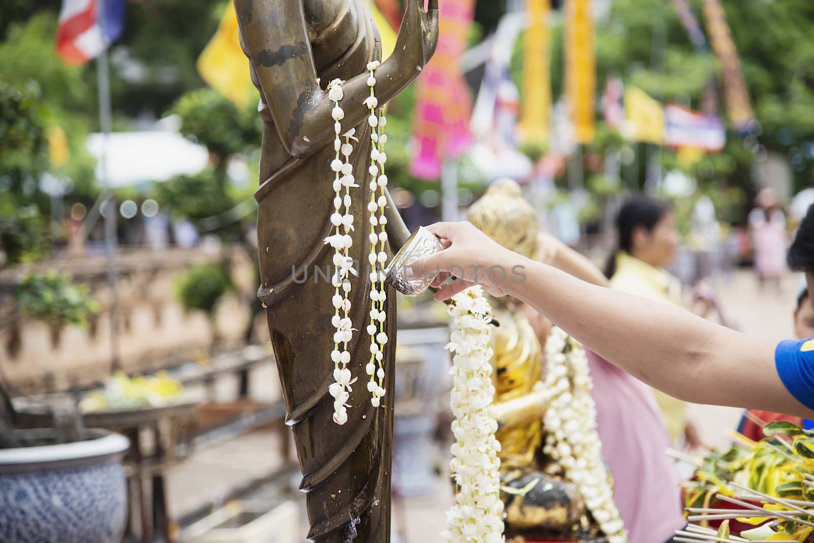 People pouring water onto a Buddha image this is a gesture of worship - people participate the local annual Chiang Mai traditional Bhudist festival. by pairhandmade