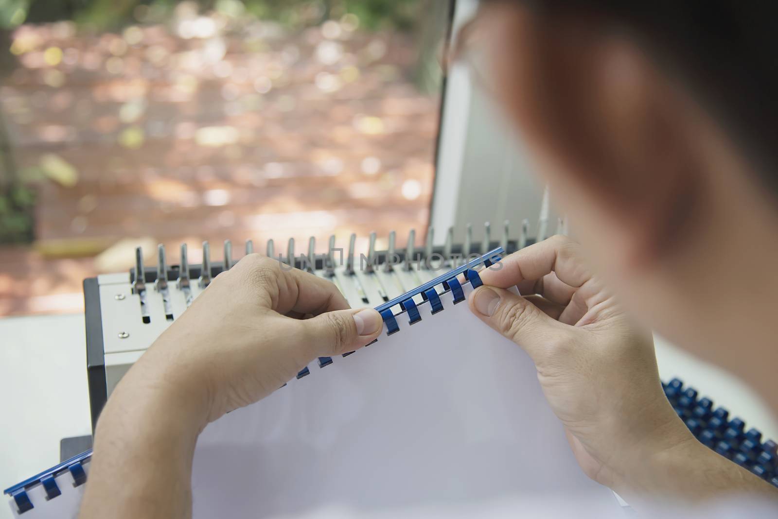 Man making report using comb binding machine - people working with stationary tools concept