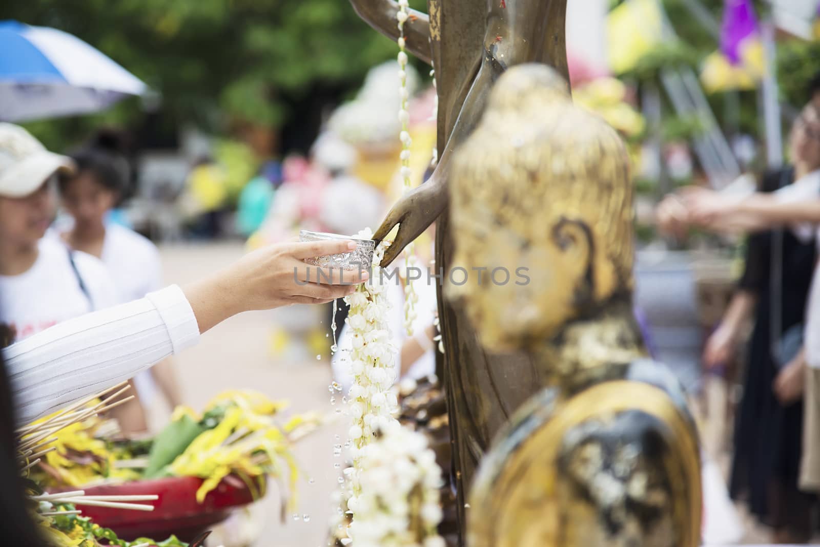 People pouring water onto a Buddha image this is a gesture of worship - people participate the local annual Chiang Mai traditional Bhudist festival. by pairhandmade