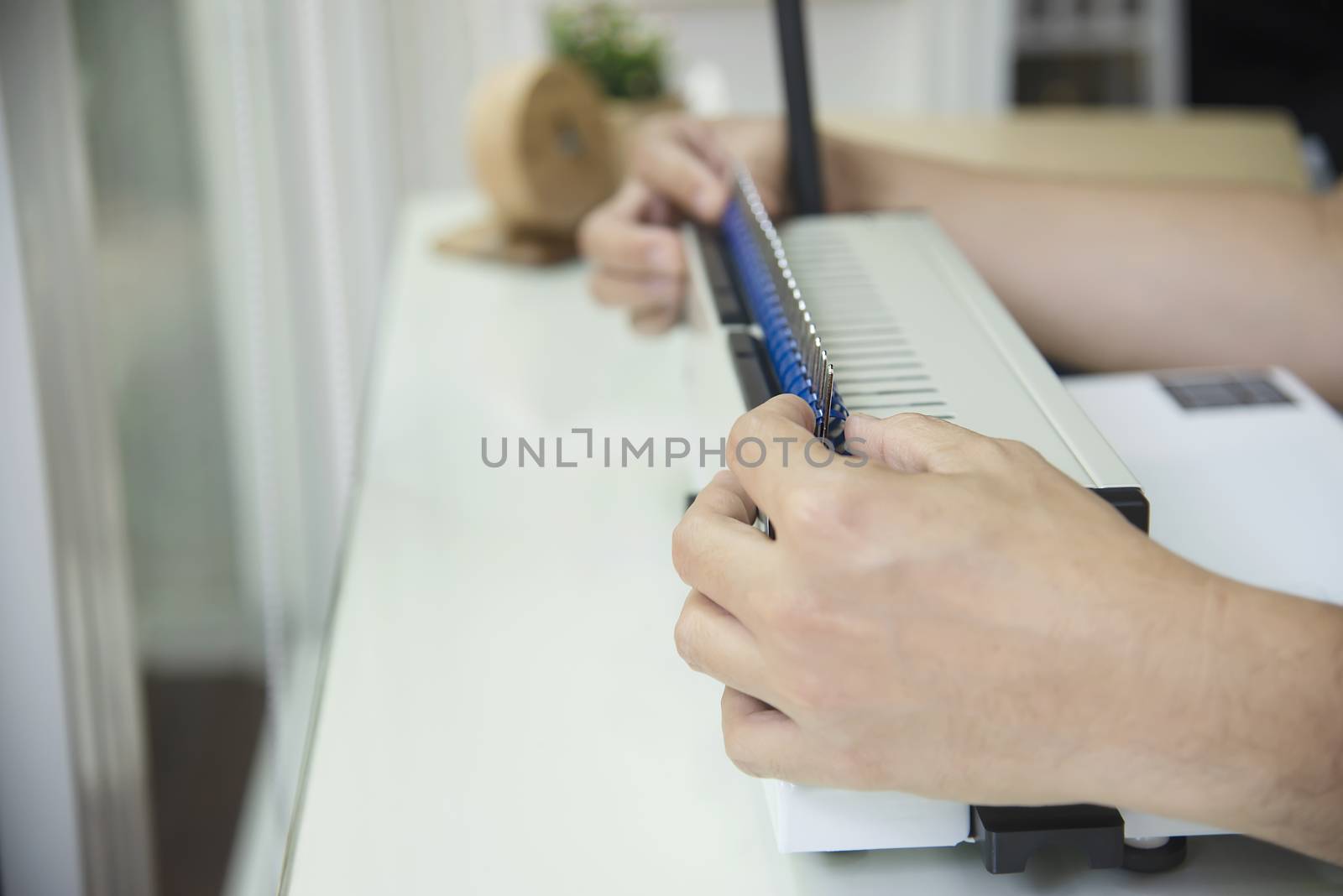 Man making report using comb binding machine - people working with stationary tools concept