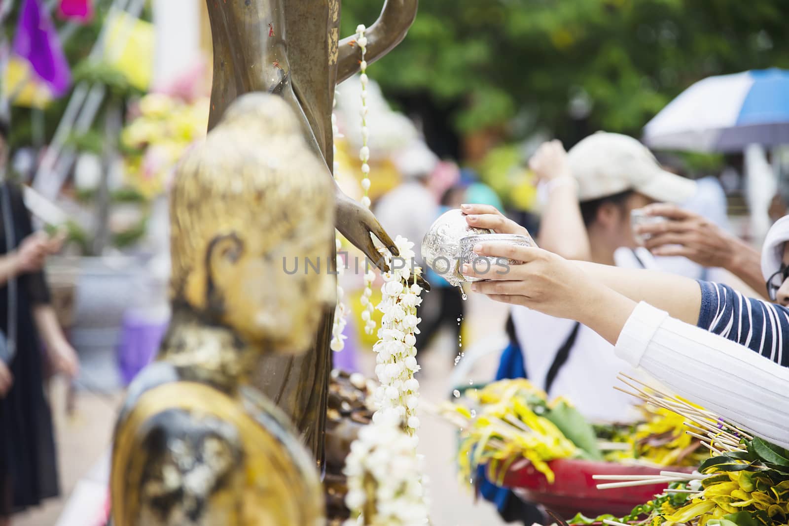 People pouring water onto a Buddha image this is a gesture of worship - people participate the local annual Chiang Mai traditional Bhudist festival. by pairhandmade